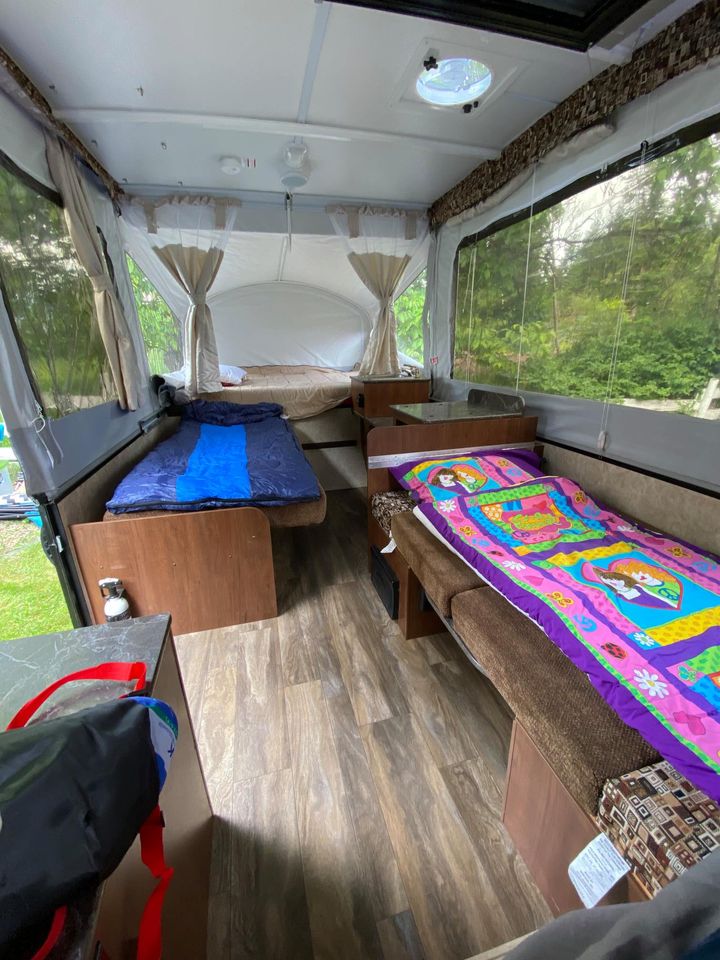 Cozy RV rental interior: Pop-up camper with multiple sleeping areas, wood-look floor, and large scenic windows.. Jayco Sport 2016
