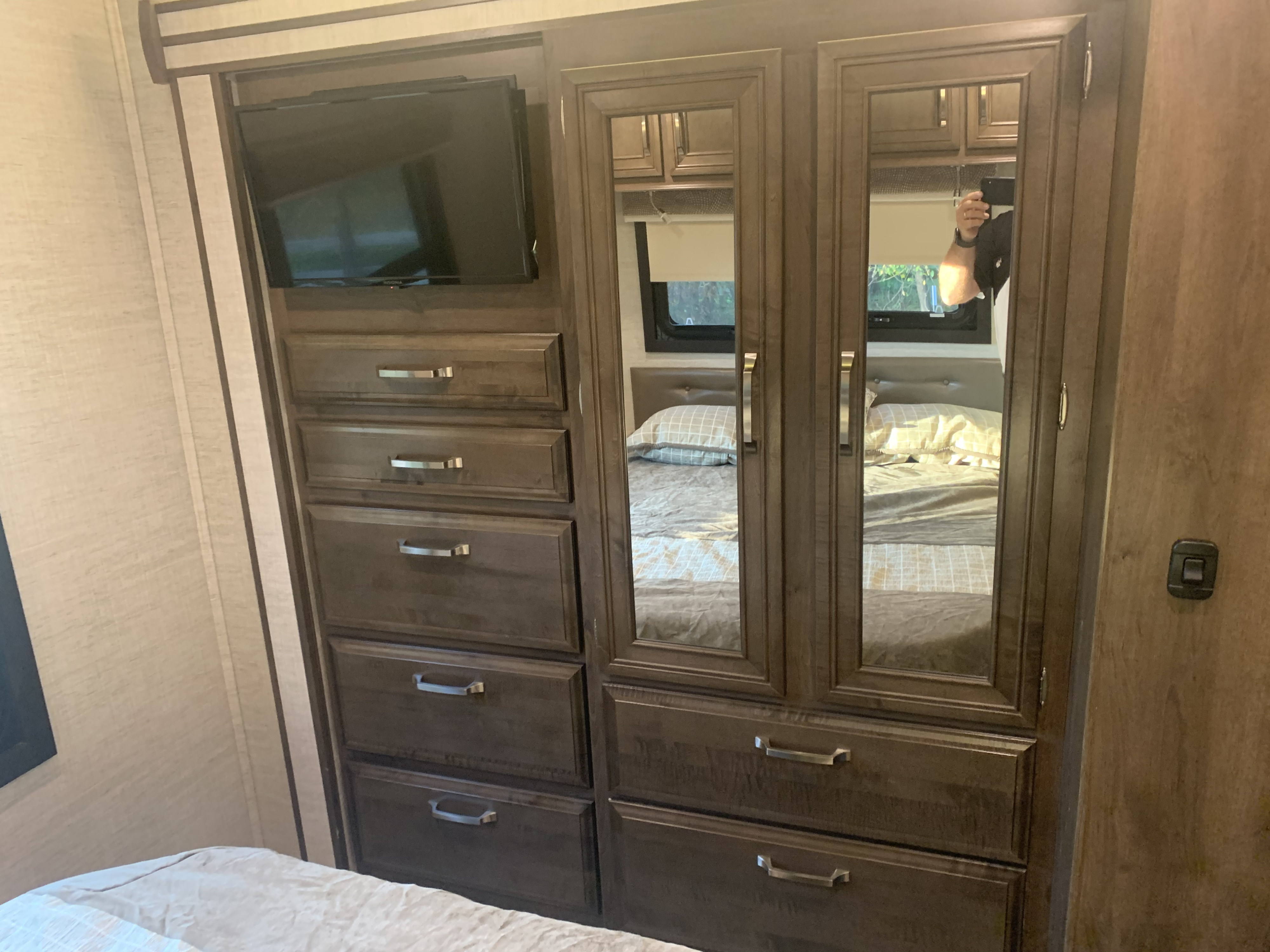 This RV rental bedroom features a built-in TV, mirrored wardrobe, and drawers for efficient storage.. Entegra Coach Esteem 2021