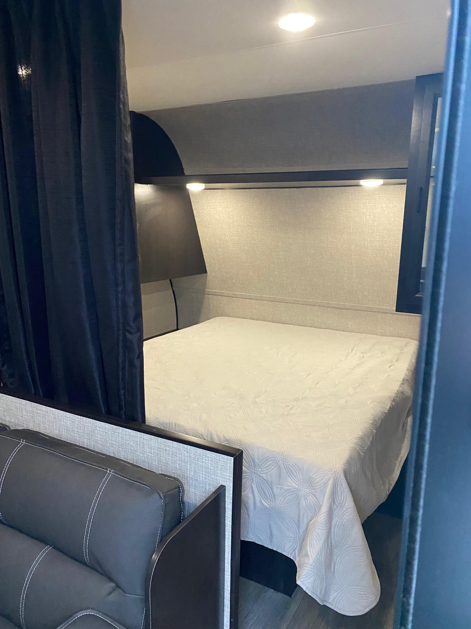 This RV rental offers a compact, inviting bedroom featuring a clean bed, overhead lights, and privacy curtains.. Jayco Jay Flight SLX8 264BH 2022
