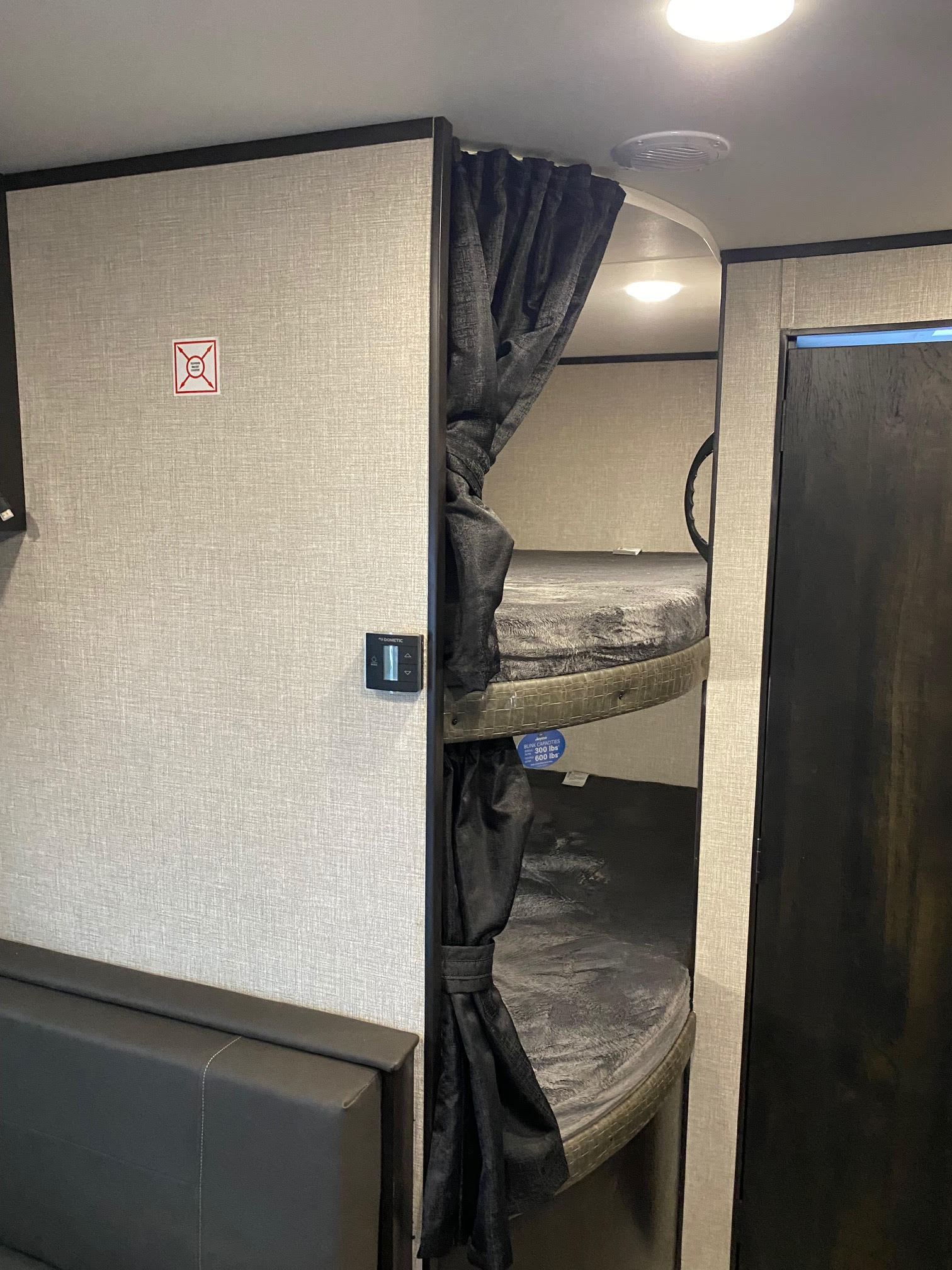 Cozy RV rental interior: functional bunk beds with privacy curtains, climate control, and safety labels for comfortable travel.. Jayco Jay Flight SLX8 264BH 2022
