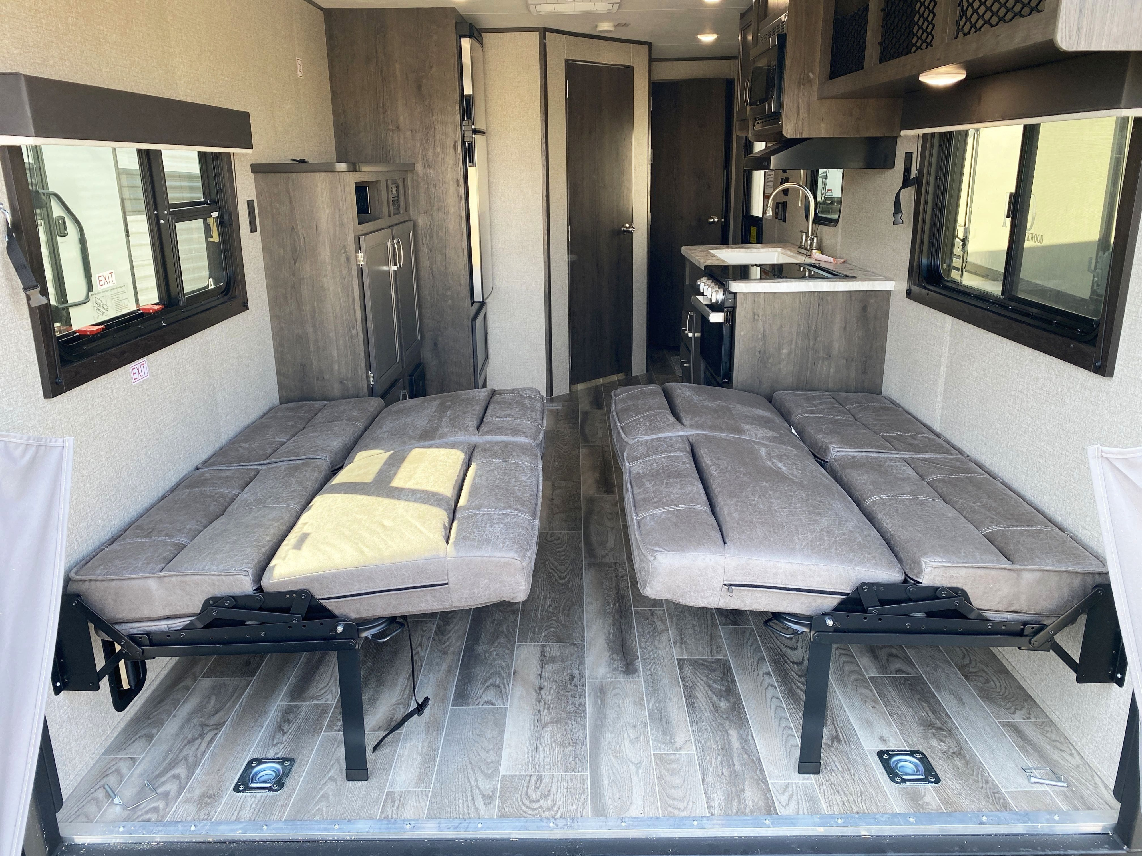 Inside an rv rental: modern interior features two convertible bench beds, a full kitchen, and stylish wood-look flooring.. Jayco Jay Flight 2021