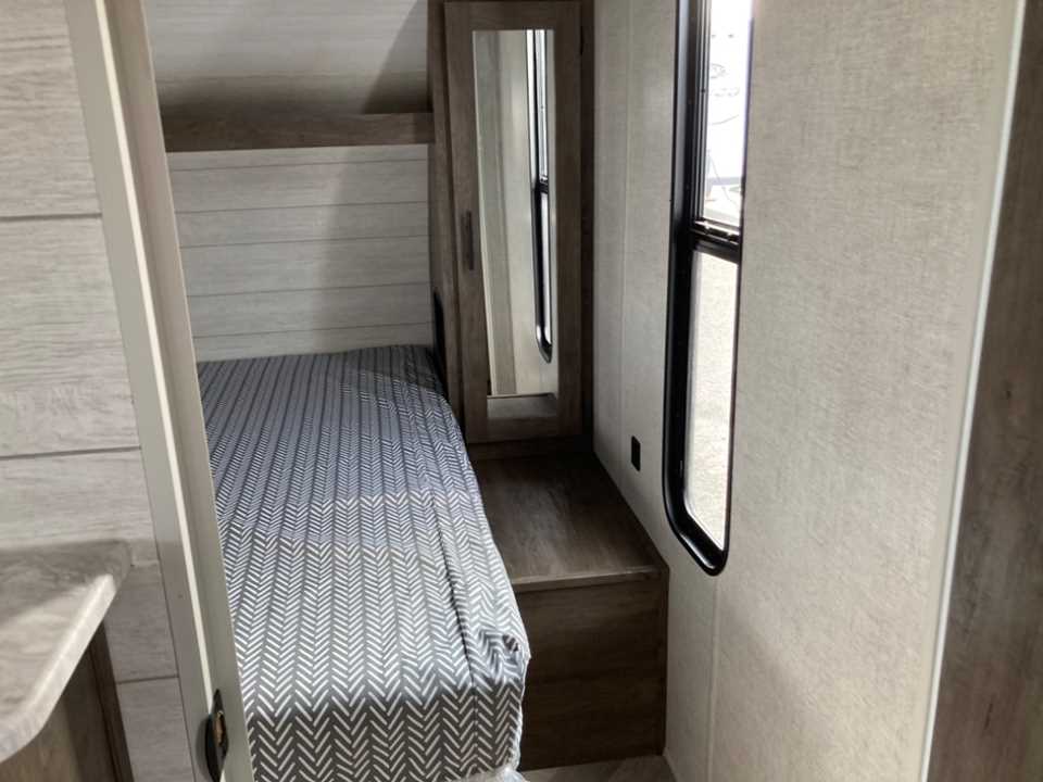 RV rental bedroom: a cozy narrow space with a patterned single bed, side mirror, and window with blind.. Forest River Salem Cruise Lite 2020