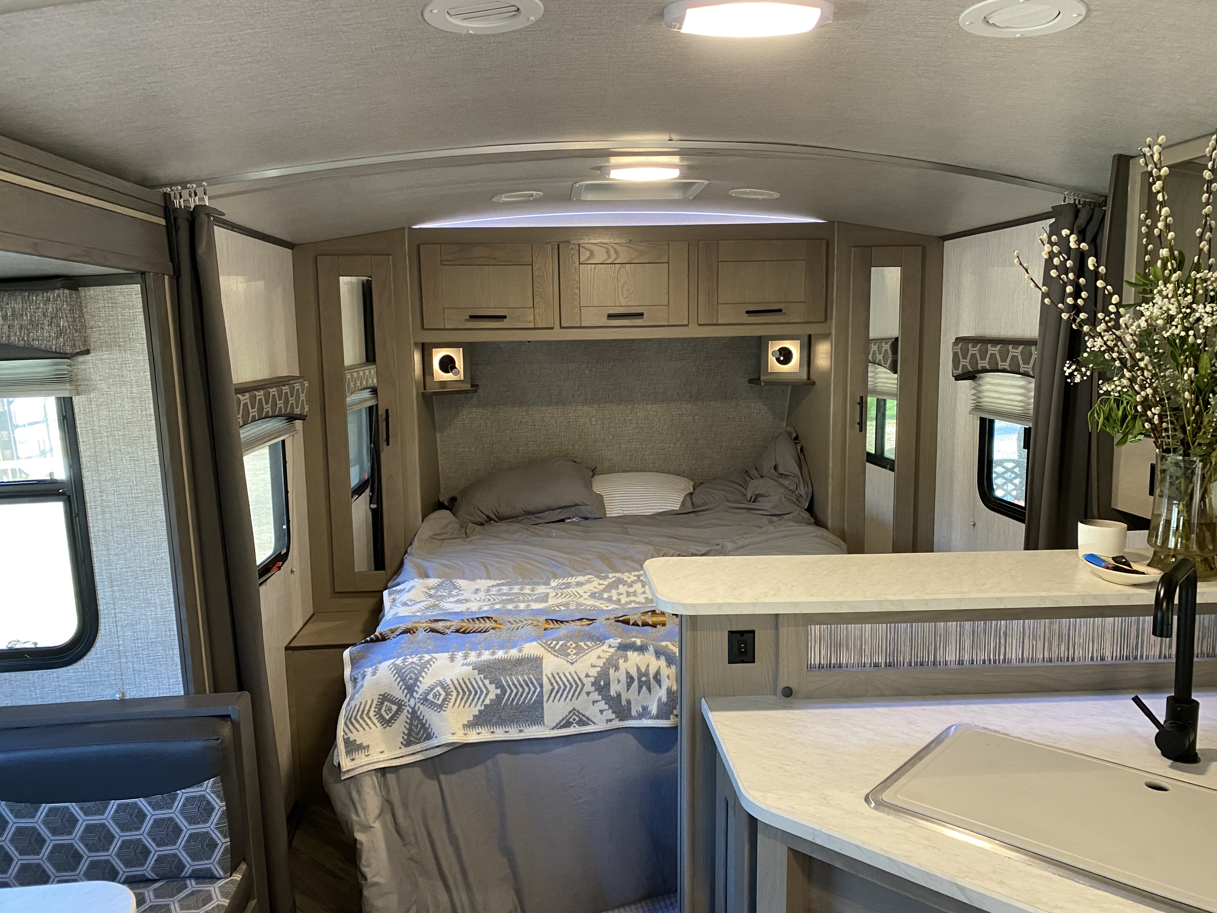 Explore this cozy RV rental interior: a comfy bedroom with storage and a practical kitchen area, perfect for travel.. Shadow Trailers Cruiser 2020