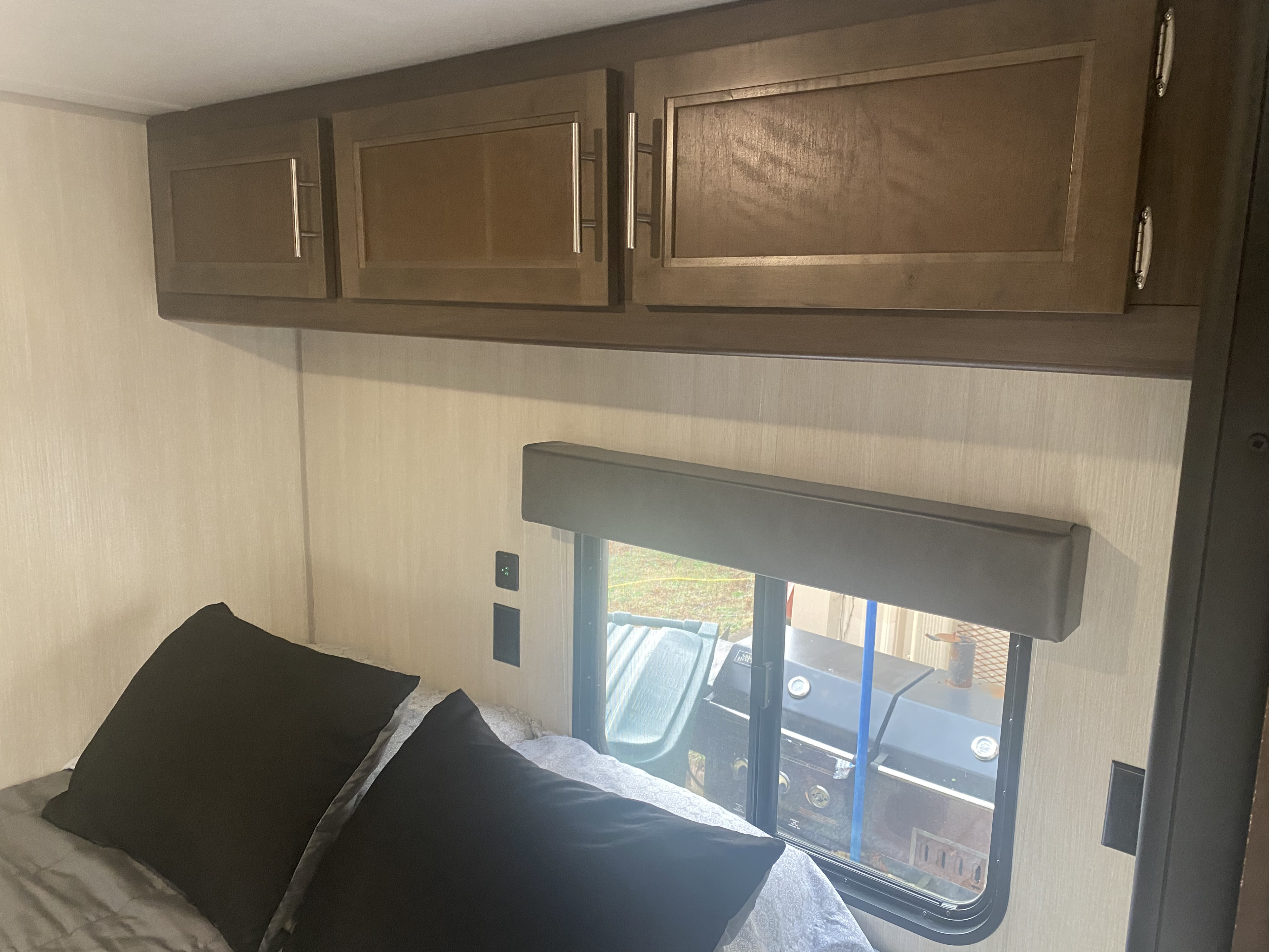RV rental bedroom: cozy bed, overhead cabinets, window view, and charging ports for a comfortable stay.. Forest River Cherokee Grey Wolf 2019