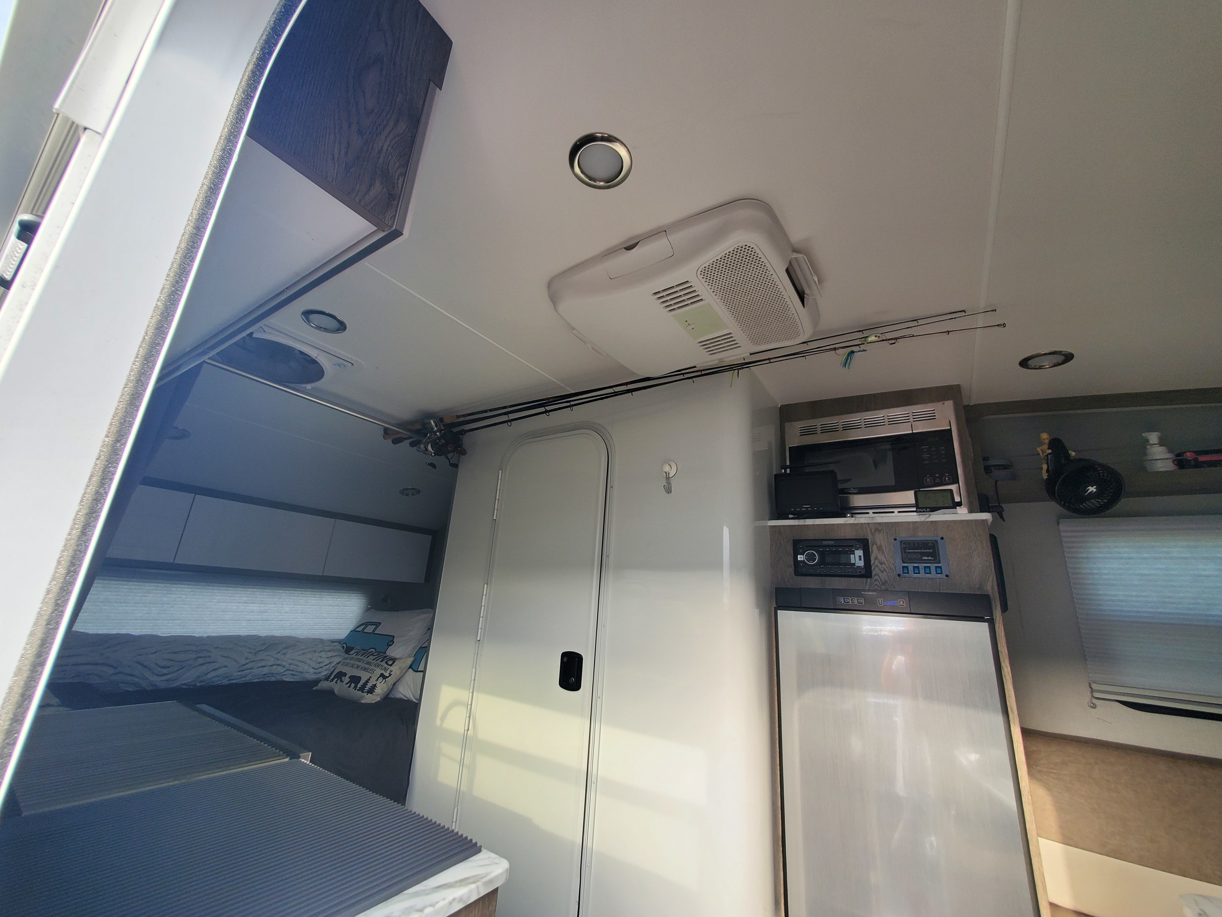 This RV rental interior highlights a functional design with a compact kitchen, sleeping area, and overhead fishing rod storage.. InTech RV Sol Horizon 2020