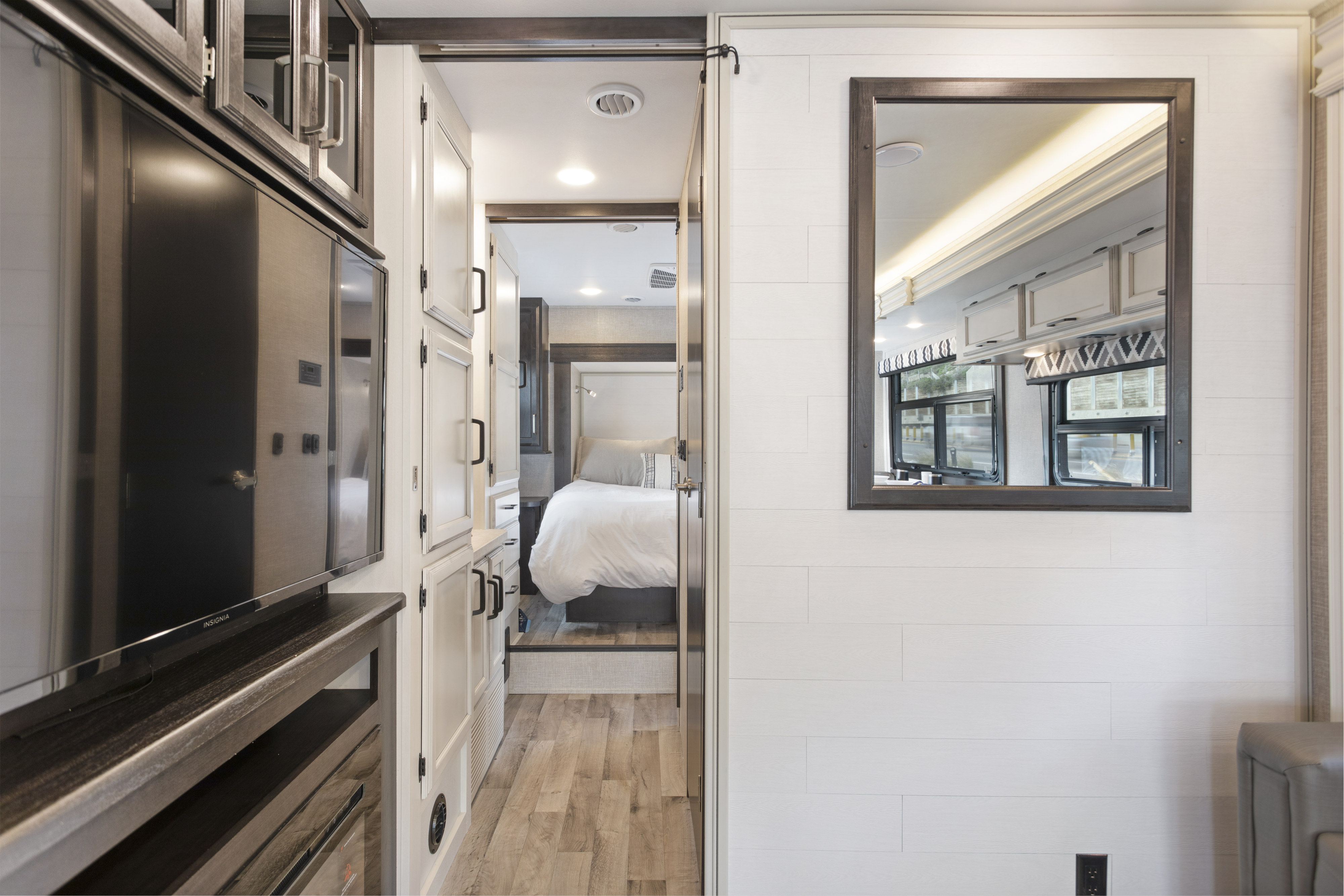 A bright RV rental interior showing a comfortable bedroom, living area with a large mirror, and functional storage space.. Other Other 2022