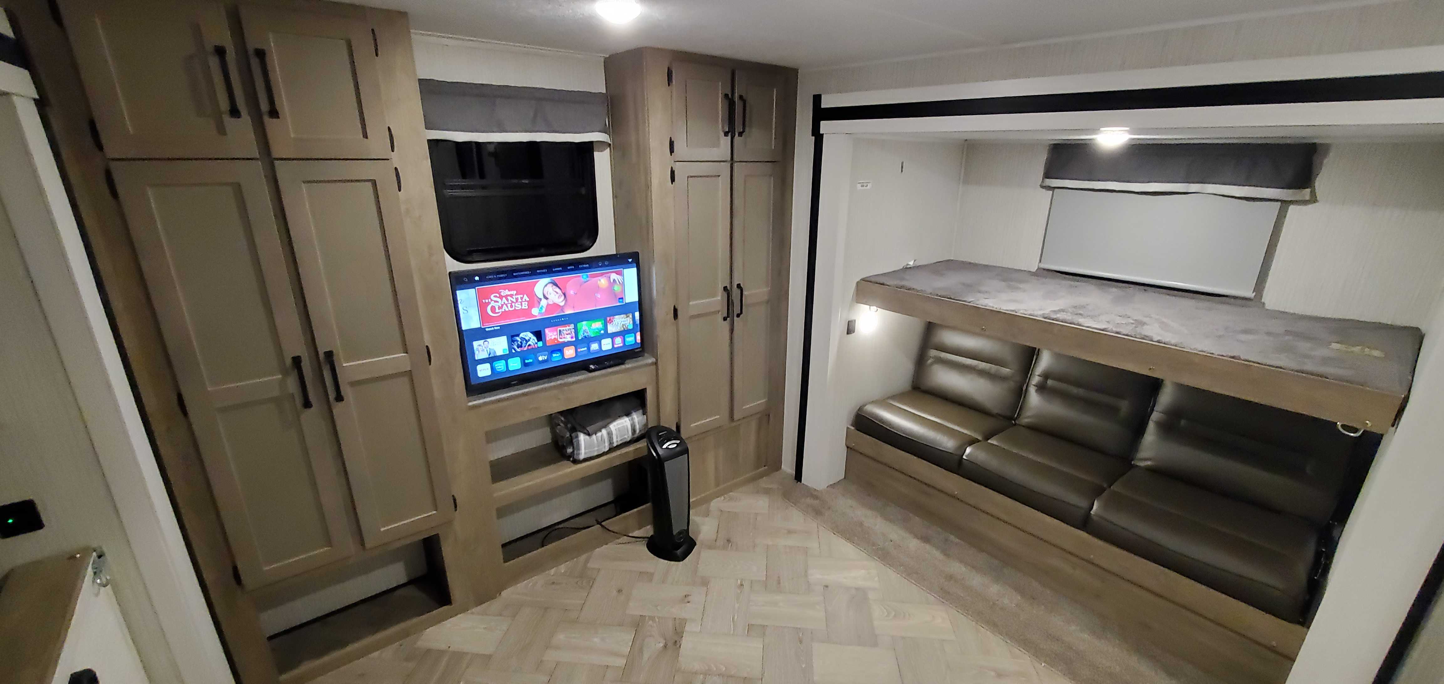 Spacious RV rental interior featuring a TV, ample storage, and comfortable bunk beds over a sofa, perfect for travel.. Palomino Puma 2021