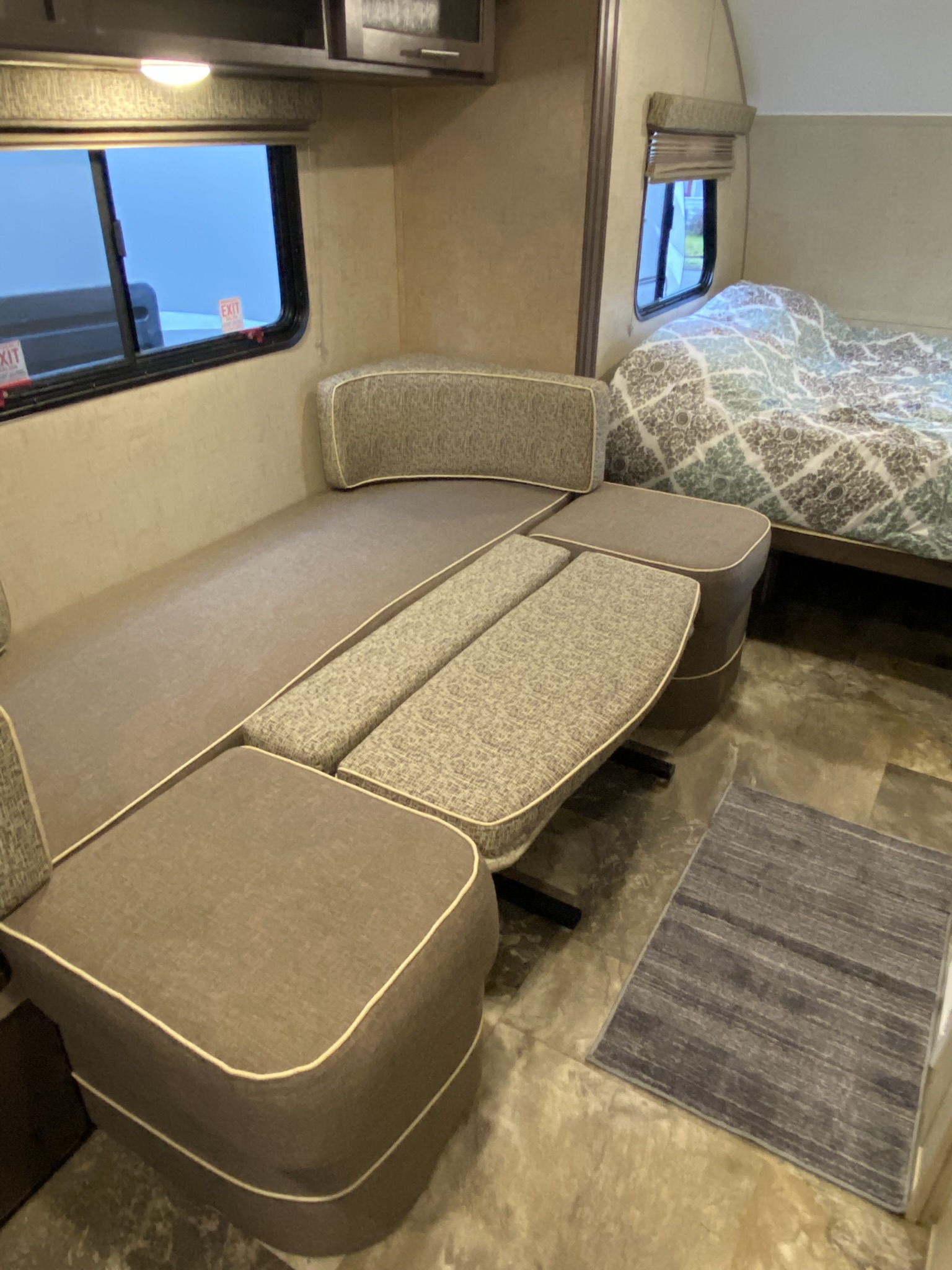 Bright RV rental interior showing modular cushioned seating (dinette), extending towards a cozy bed in the background.. R-Pod Hood River Edition 2017