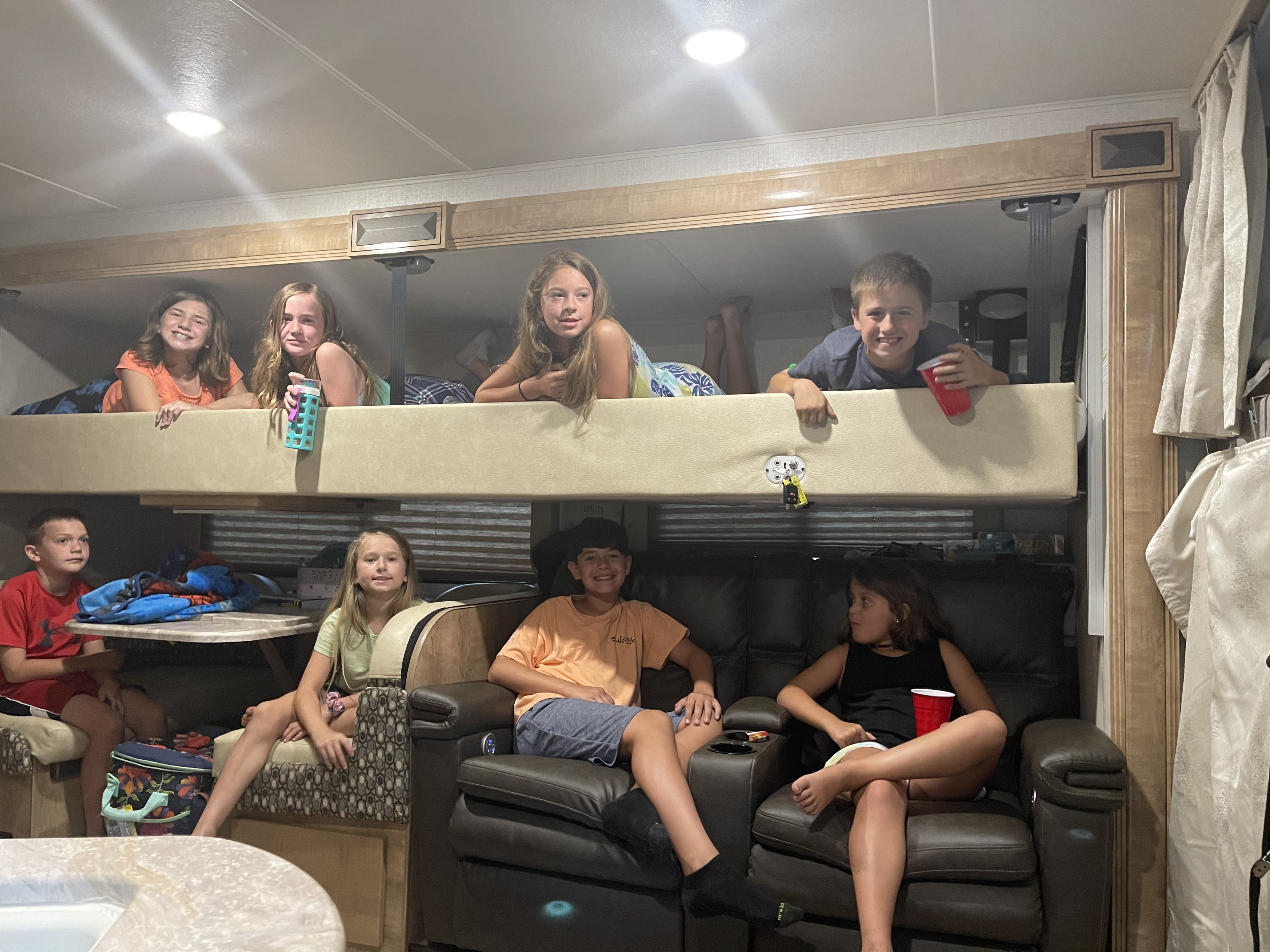 Children enjoying an RV rental, with some on upper bunk beds and others on seating below, all smiling in the cozy interior.. Forest River Coachmen Leprechaun 2019