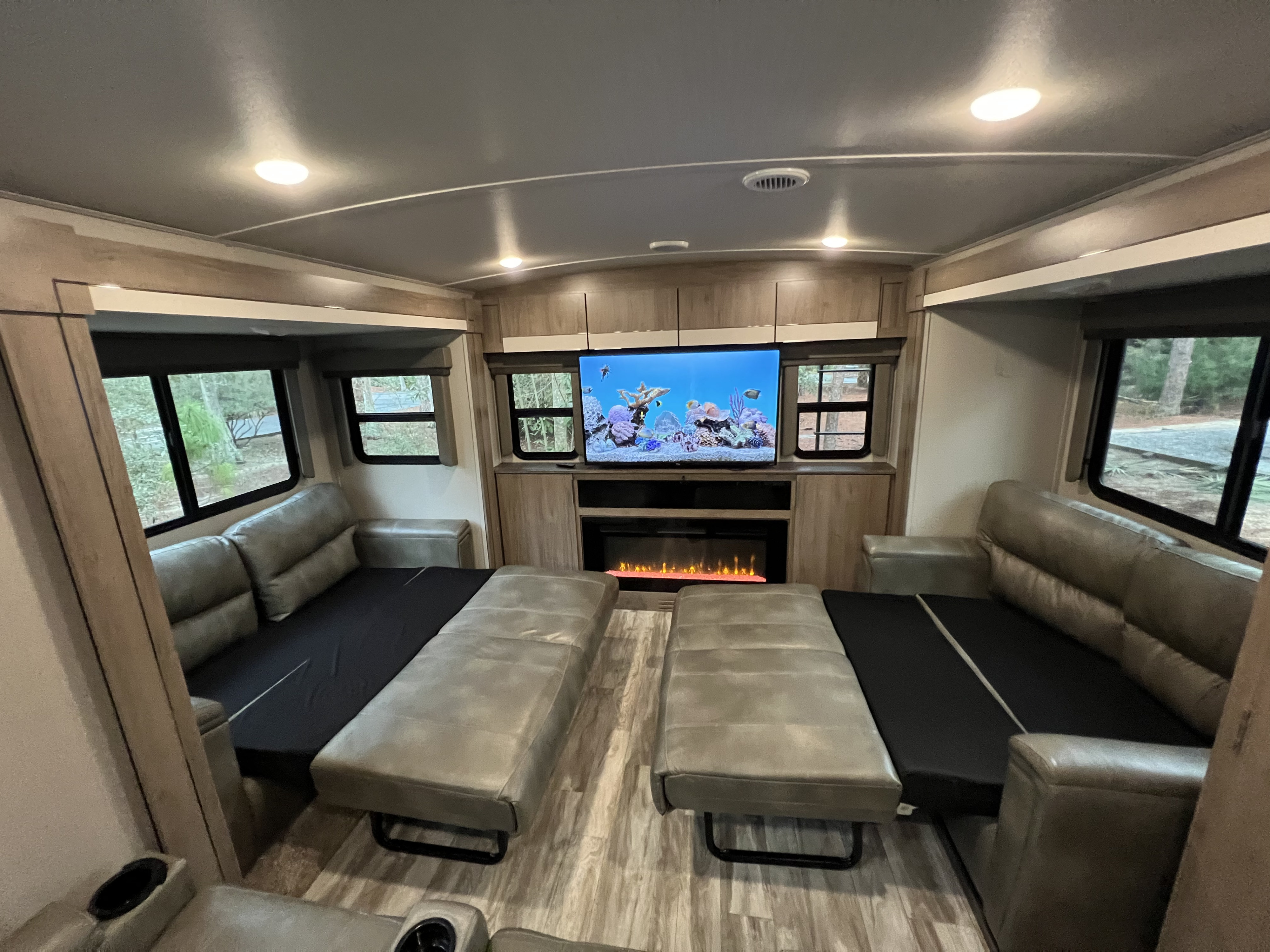 Spacious RV rental living area with convertible sofas, TV, and fireplace for cozy travel comfort.. Grand Design Imagine 2020