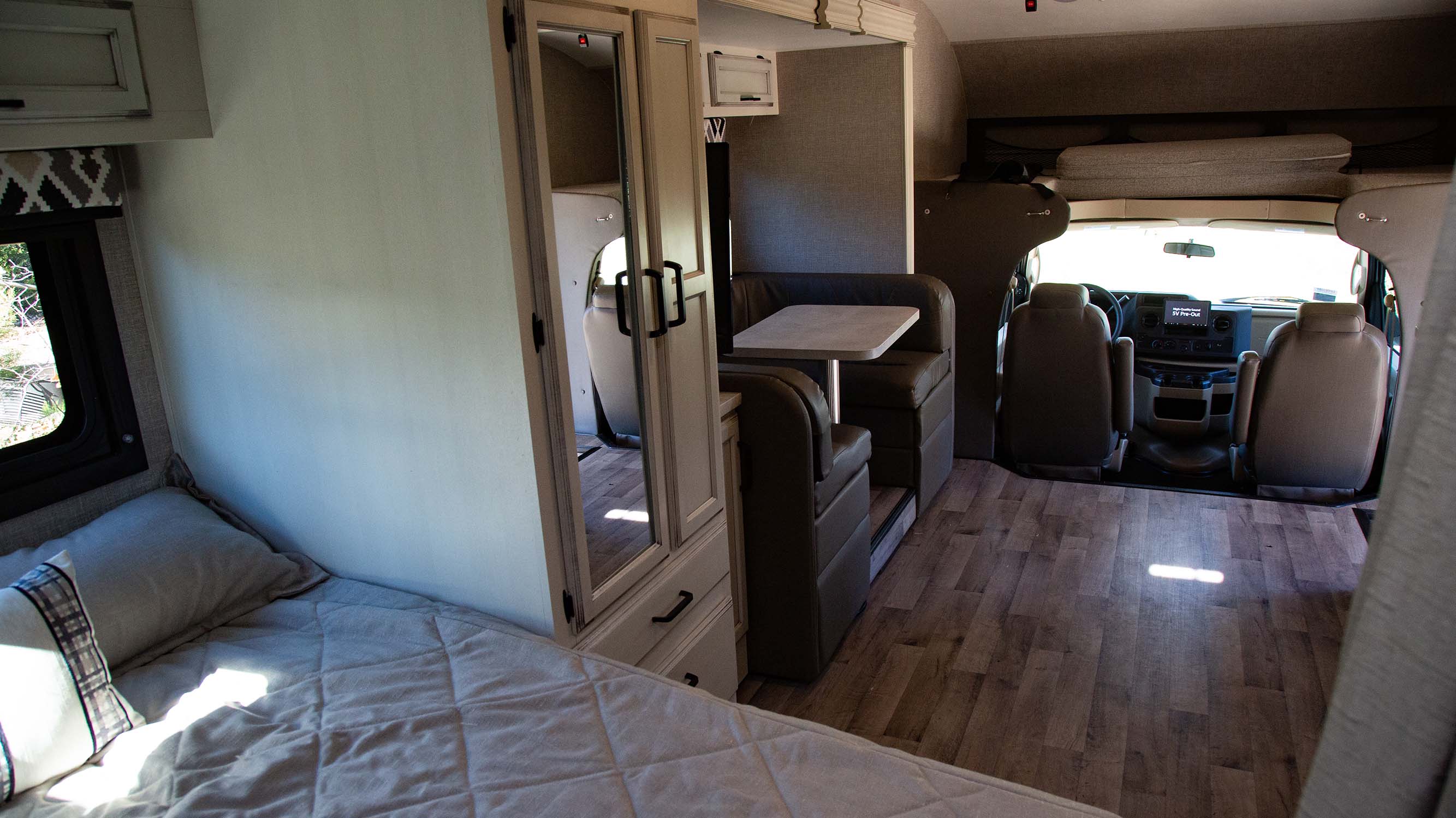 Inside a comfortable RV rental: bed, dinette, driver's cab, and overhead bunk. Ideal for road trips.. Jayco Redhawk 2022