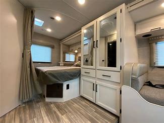 Inside an RV rental: a bright, modern interior with a bed, mirrored storage, and dinette seating for comfortable travel.. thore Freedom Elite 24HE 2022