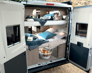 View into an RV rental camper van with open rear doors, revealing a cozy interior featuring comfortable bunk beds.. CI kyros 2023