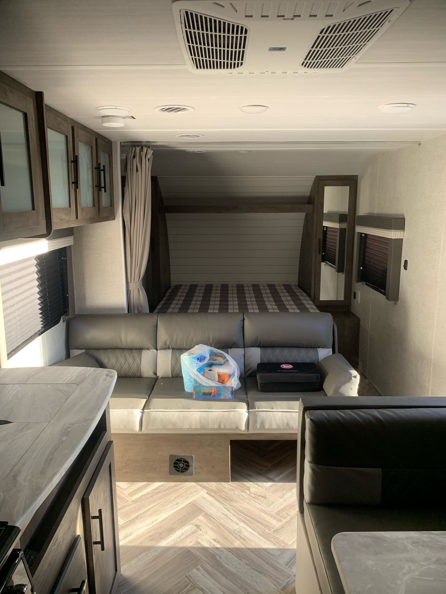 An RV rental interior: sofa, kitchen counter, and bed. Shows the modern living space and bedroom of a camper.. Forest River Salem Cruise Lite 2021