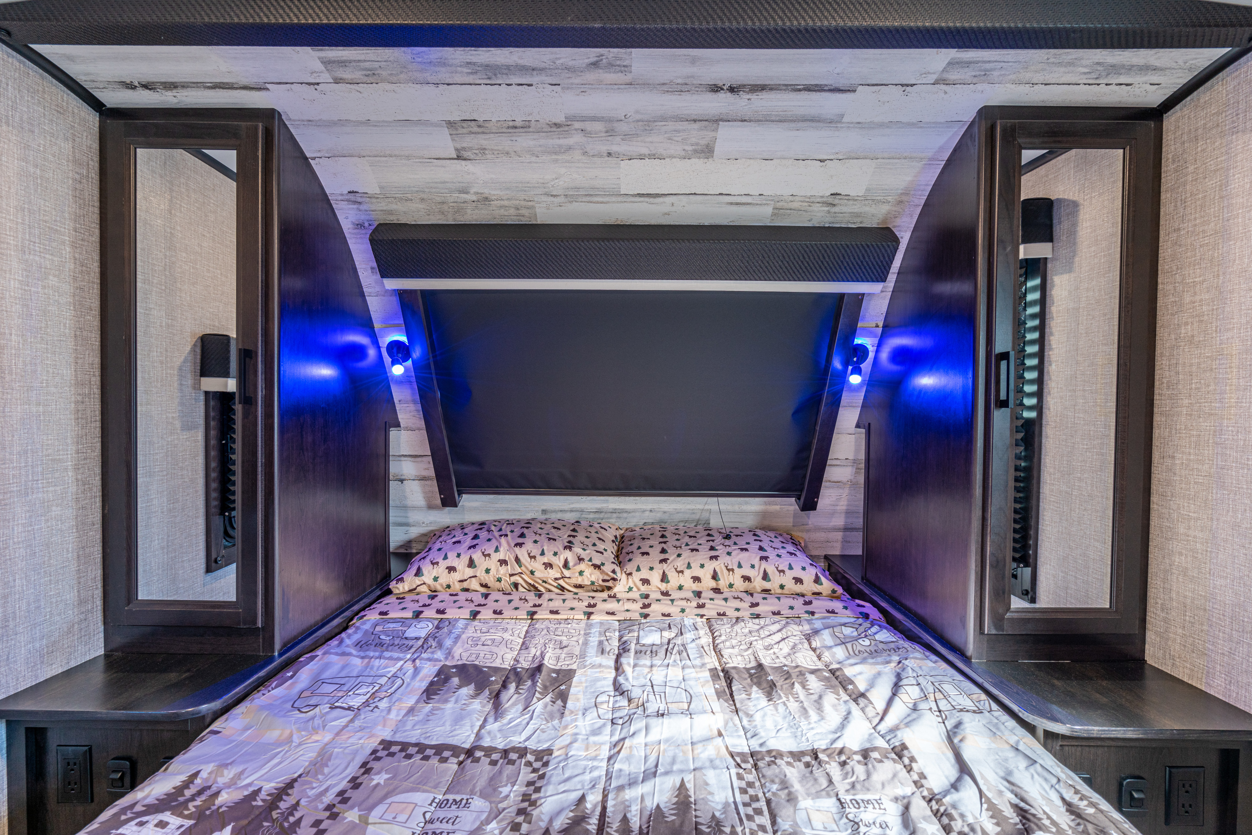 Experience comfort in this cozy RV rental bedroom, featuring nature-themed bedding, blue accent lights, and practical bedside storage.. Jayco White Hawk 29BH 2022