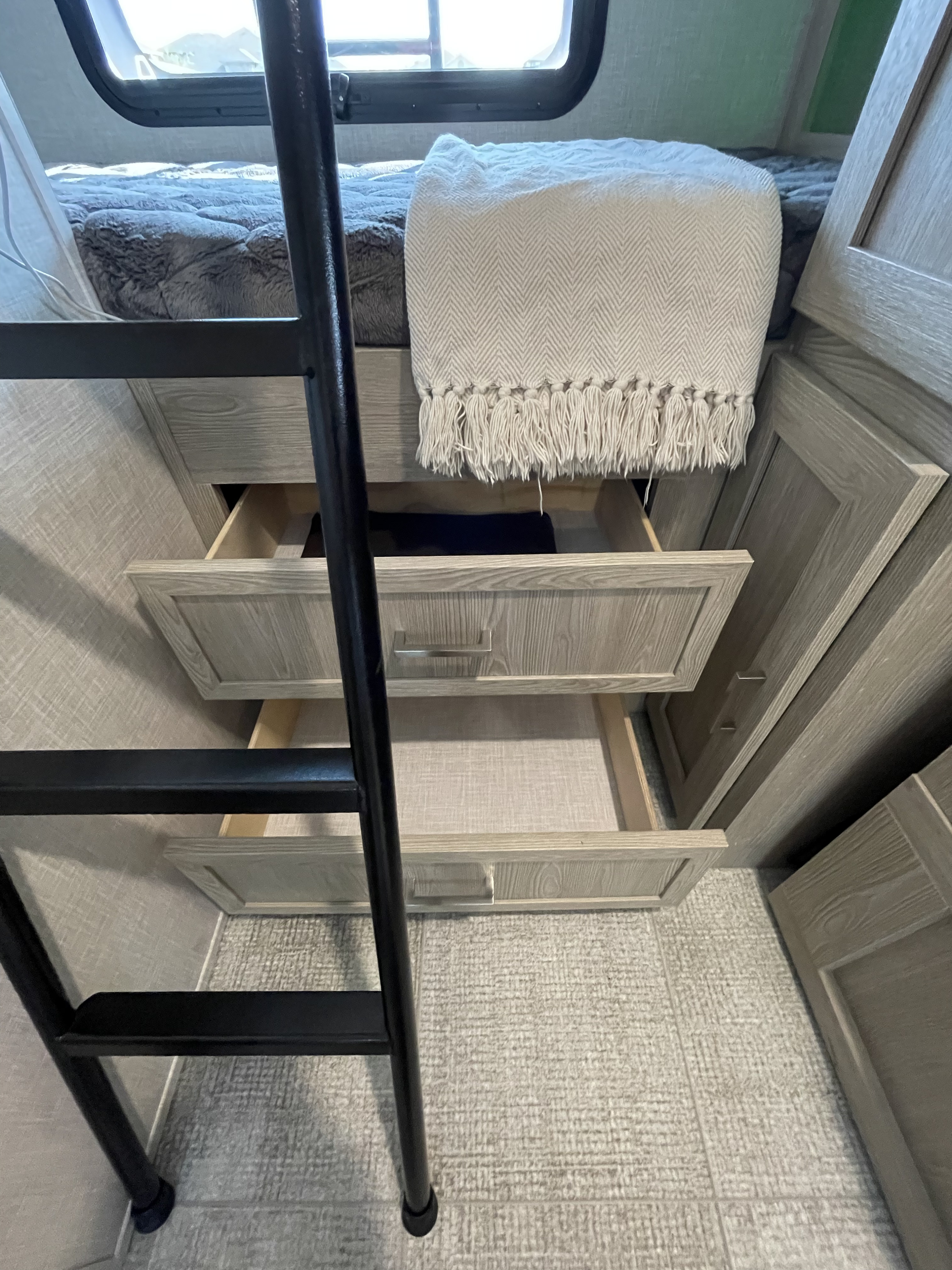Cozy RV rental interior featuring bunk beds with a ladder, ample storage in open drawers, and a plush throw.. Forest River Flagstaff E-Pro 2021