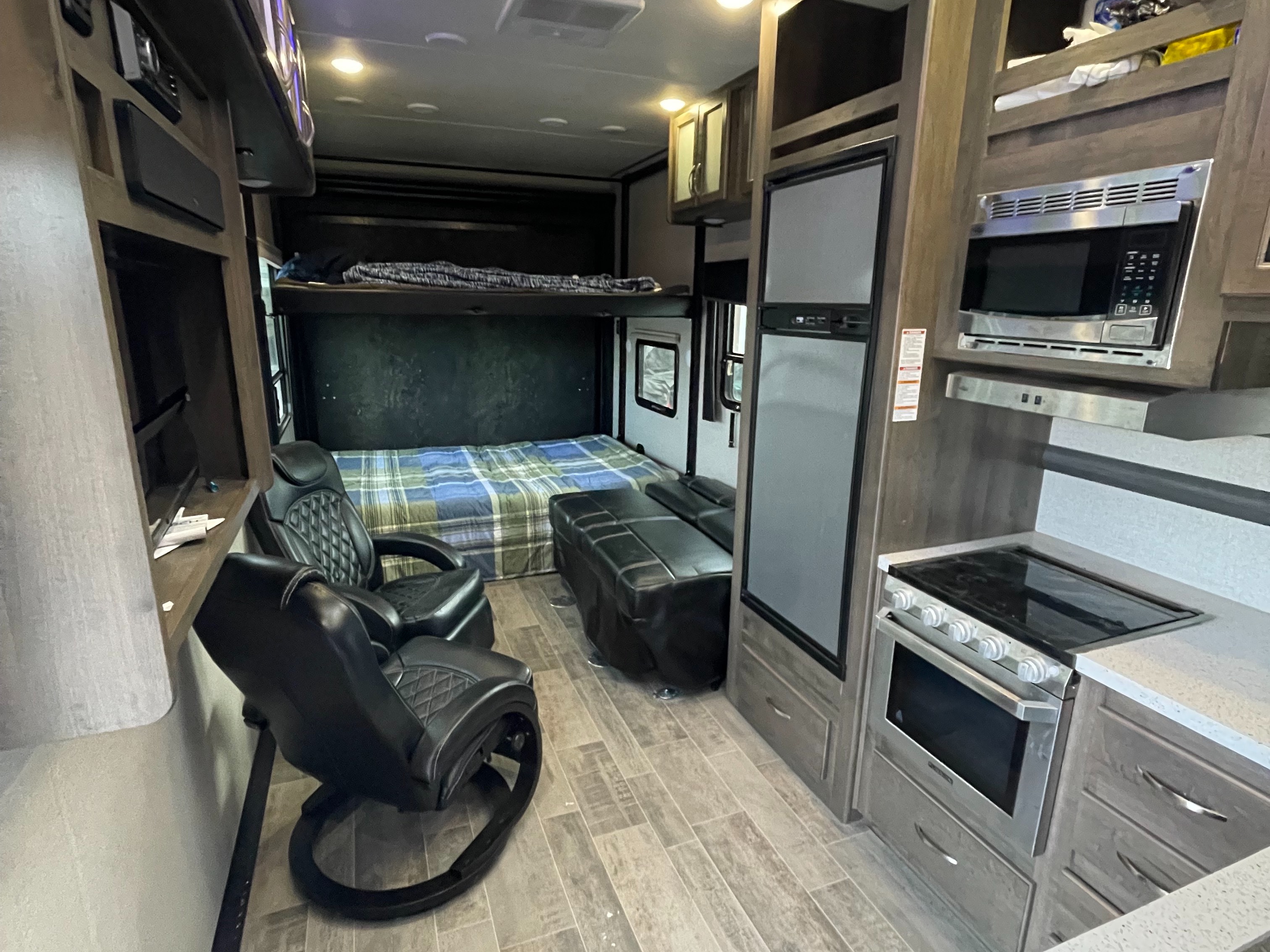 Well-equipped rv rental interior: full kitchen appliances (stove, microwave, fridge), bunk bed, main bed, and two comfortable recliners.. Dutchmen Voltage 2018