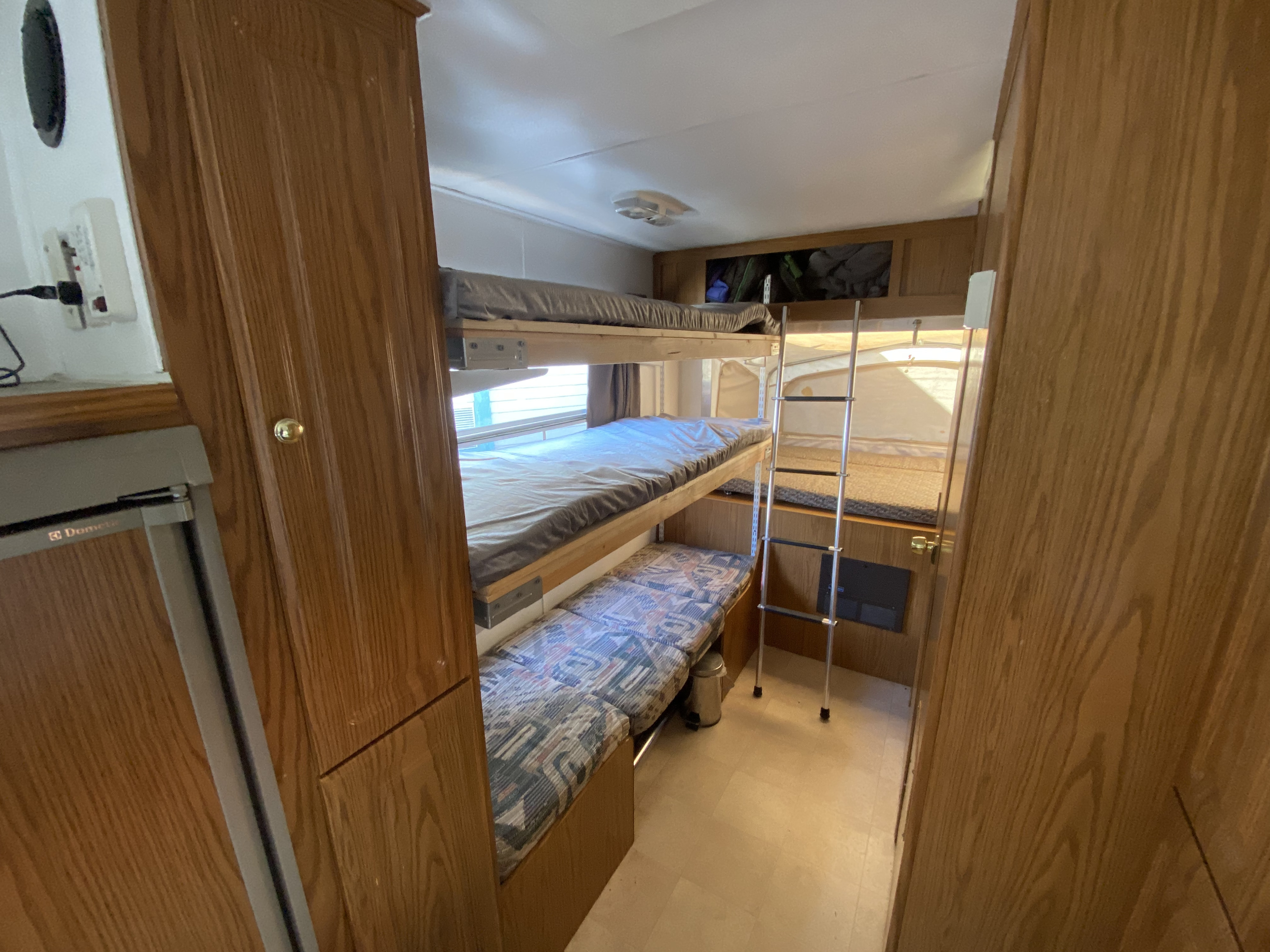 RV rental interior featuring bunk beds, a ladder, and a compact sleeping area with wood accents. Ideal for family trips.. Starcraft Travel Star 2002