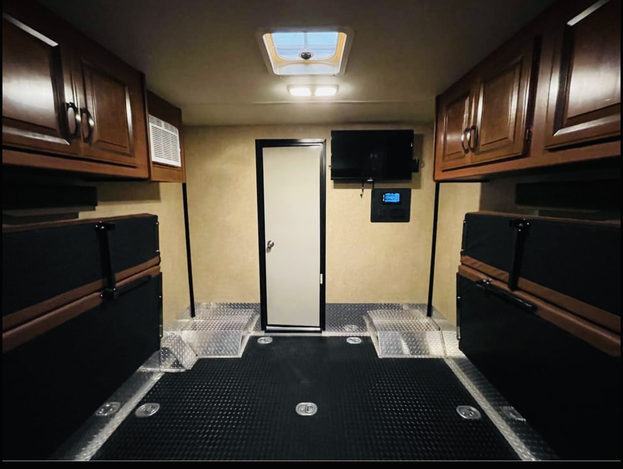 RV rental: Interior of a toy hauler with durable floor, overhead cabinets, TV, and fold-up beds on either side.. Thor Outlaw 2014