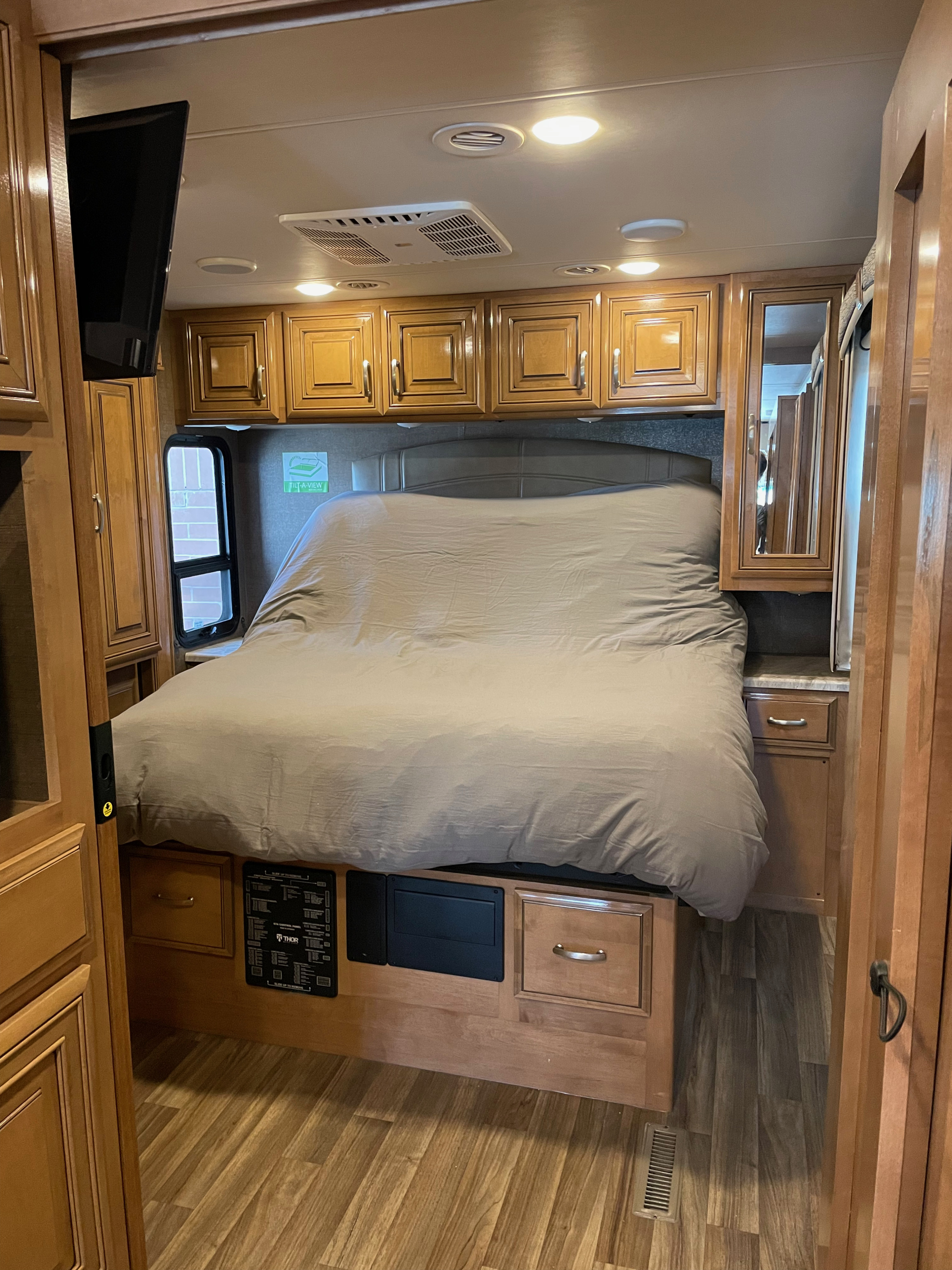 RV rental bedroom showcasing a comfortable bed, warm wooden cabinetry, and ceiling lights, creating a cozy and functional interior.. Thor Palazzo 2019