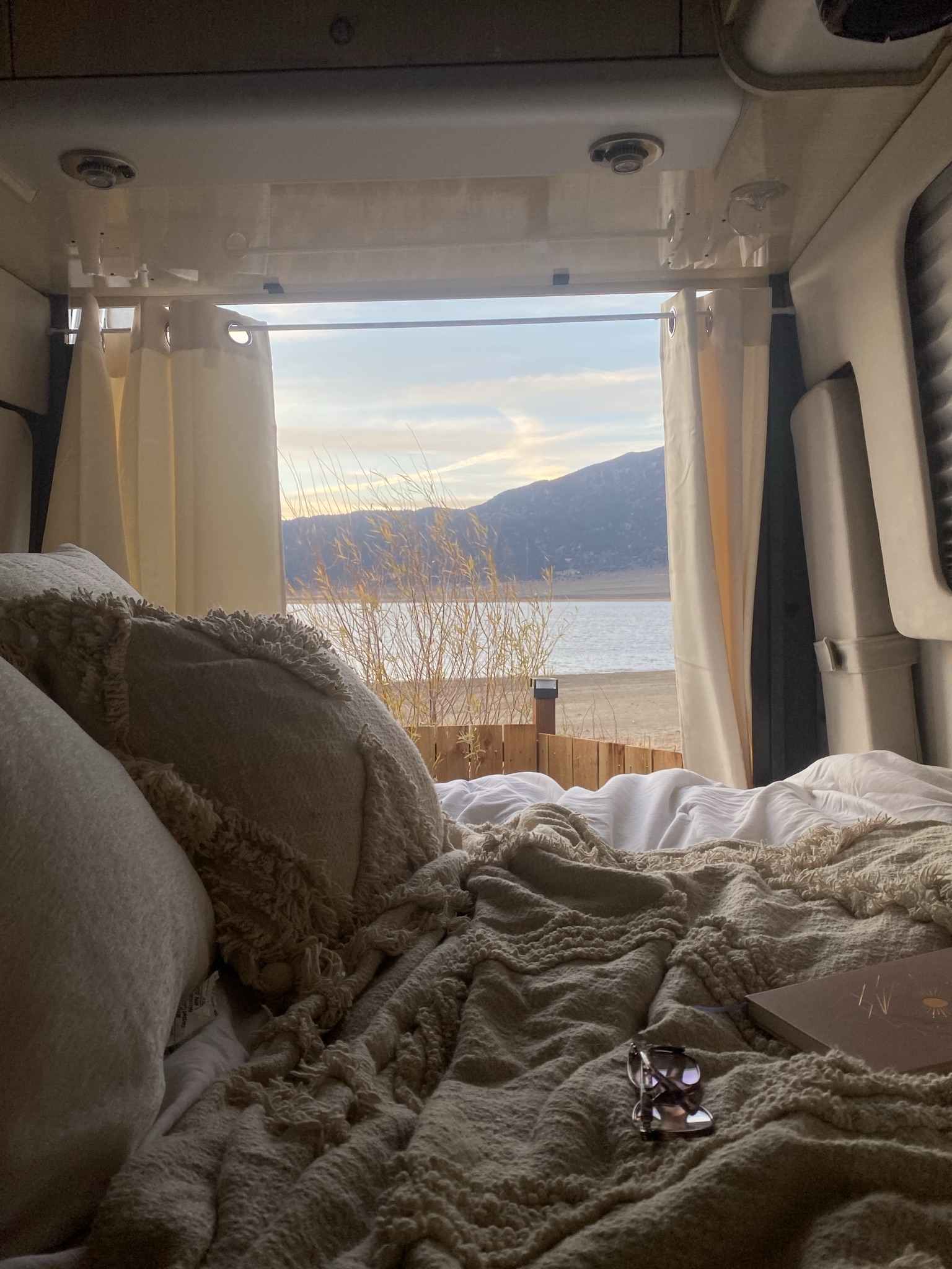 RV rental: Cozy bedroom with a stunning lake and mountain view from bed. Curtains frame nature's beauty.. Airstream Interstate 2015