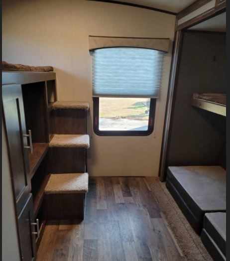 RV rental interior: bunk beds, storage steps, and window view. Compact, functional space for travel.. Cruiser RV Embrace Ultra Lite 2019