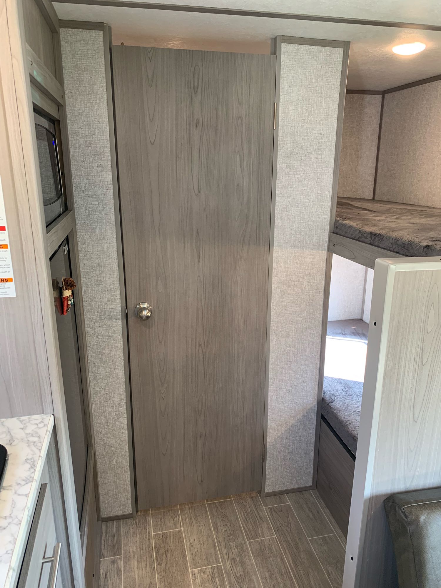 Modern RV rental interior featuring a kitchen counter, a wood-grain door, and a cozy bunk bed area.. Coleman 17B Other 2022
