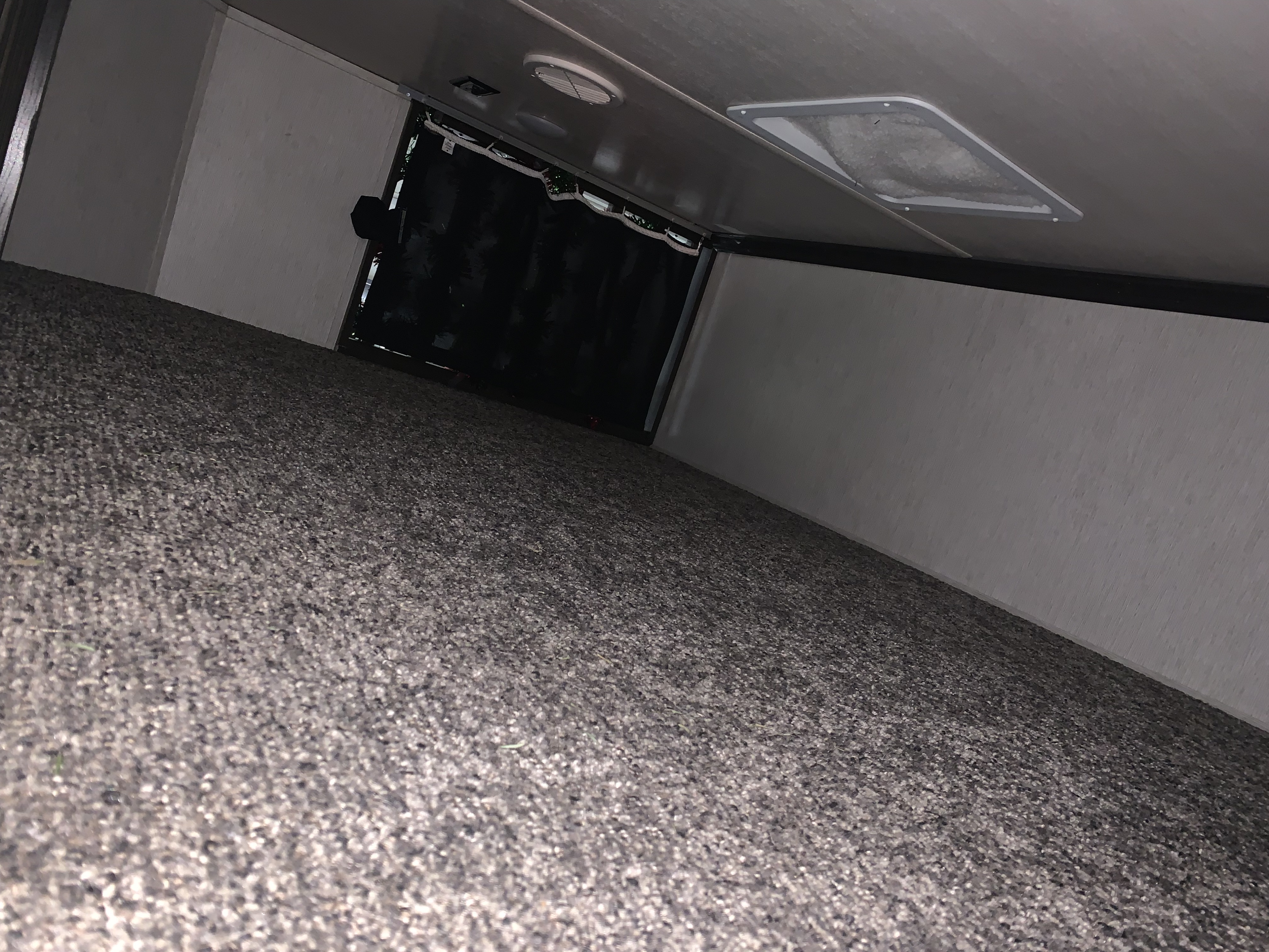 RV rental interior: Dark carpeted floor leads to a shadowy opening, framed by light walls and a vented ceiling.. Heartland RVs Elkridge 2019