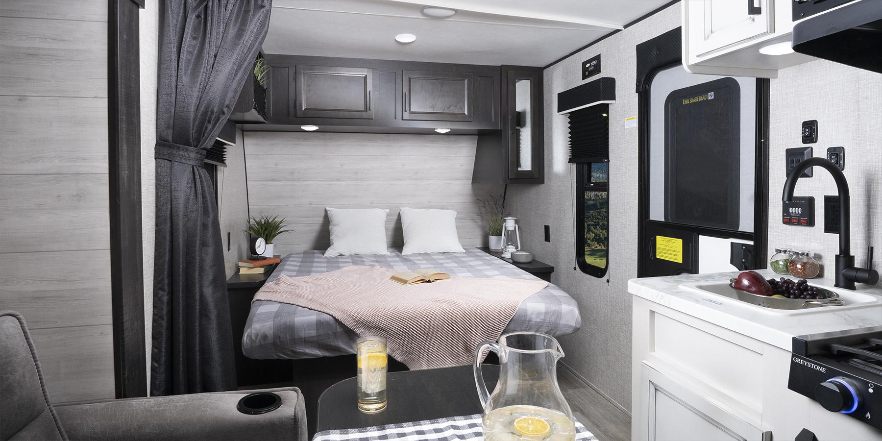 Modern rv rental interior featuring a cozy full bed, functional kitchenette with sink, and a small dining area.. Jayco Jayco 184Bs 2022