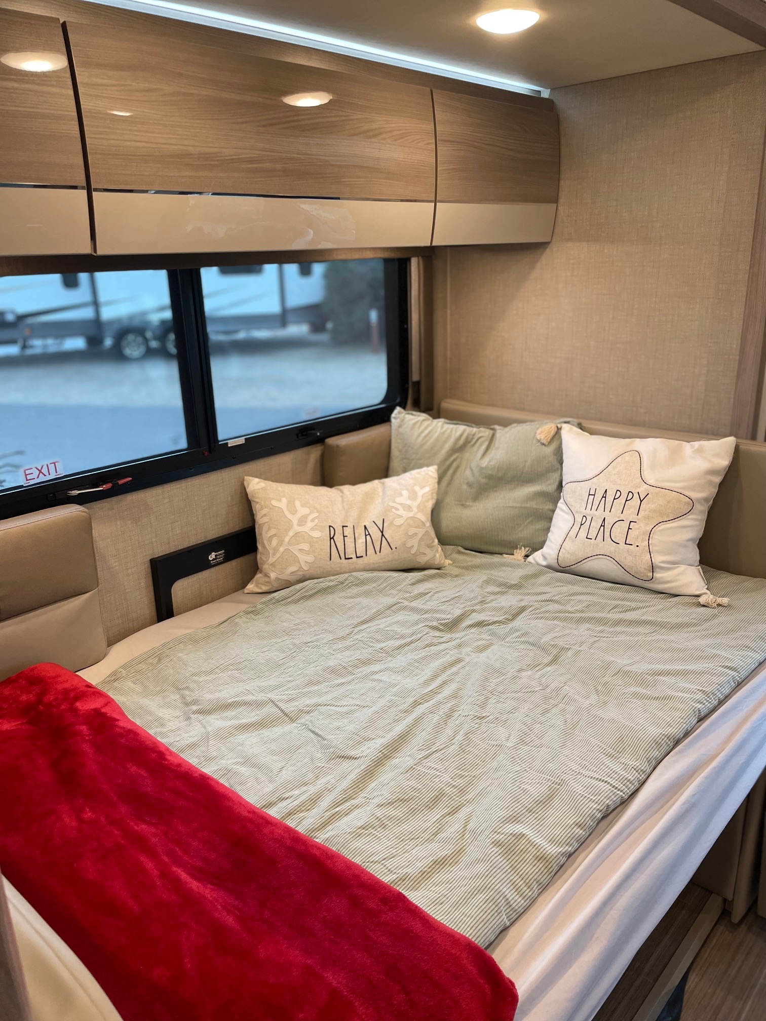 Cozy RV rental bed with "RELAX" and "HAPPY PLACE" pillows, inviting comfort for your travel adventures.. Mercedes Delano Sprinter 2022