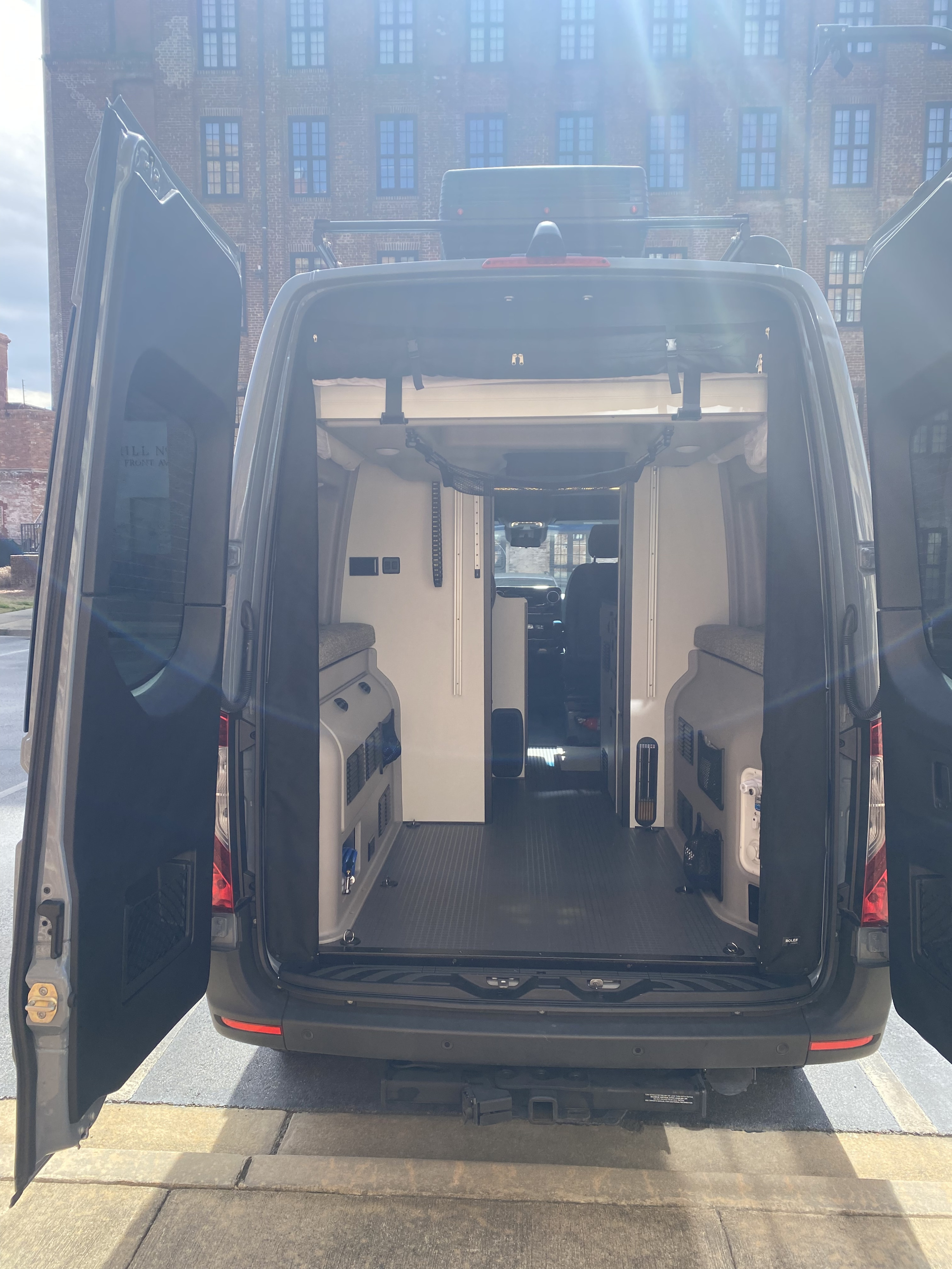 Spacious RV rental van with open rear doors, showcasing its well-equipped camper interior for travel.. Winnebago Revel 2021