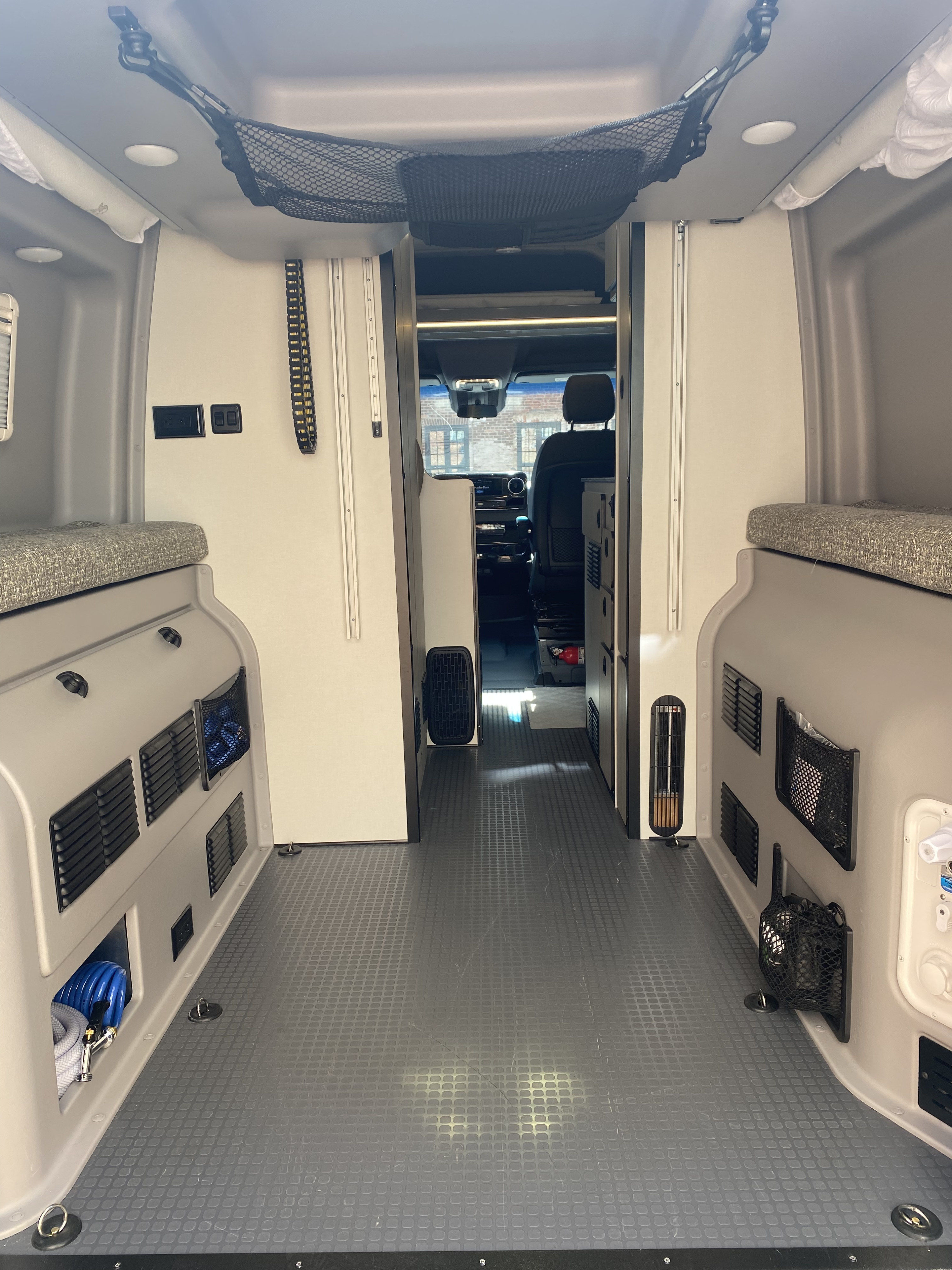 Step inside this rv rental's spacious interior, featuring flexible cargo flooring, bench seating, and access to the front cabin.. Winnebago Revel 2021