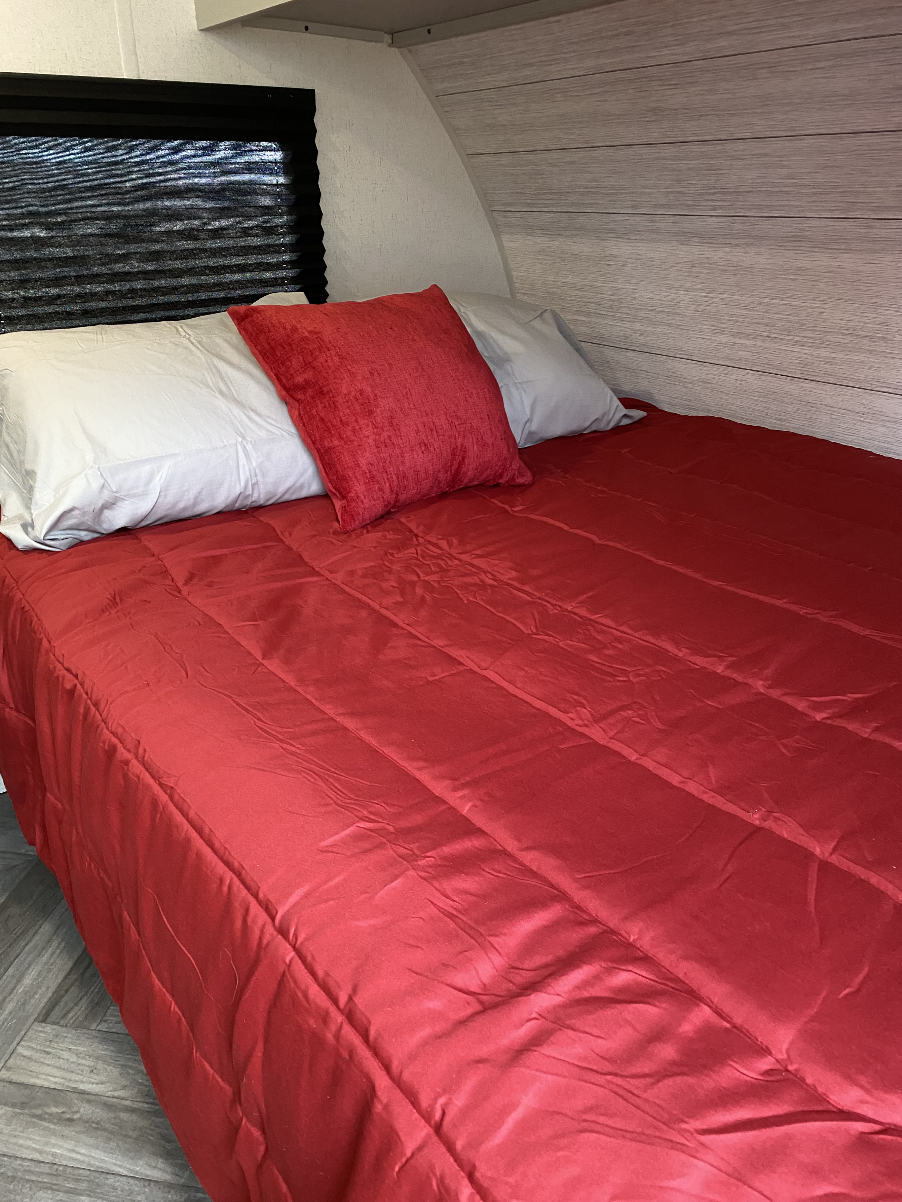 Comfortable RV rental bed featuring a bright red comforter and pillows, creating a cozy interior space.. Forest River Salem FSX 178BHSK 2022