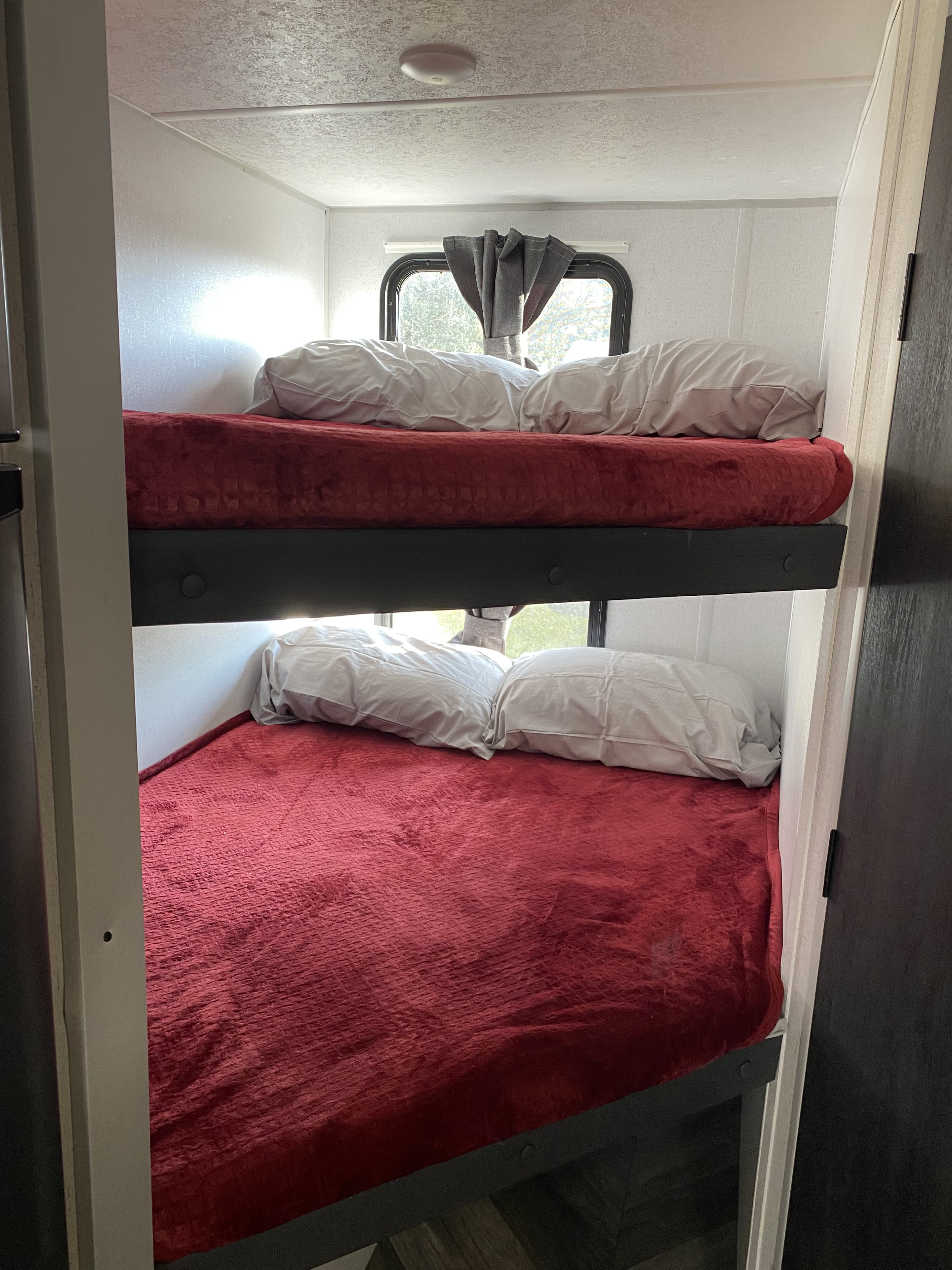 Cozy RV rental bunk beds with soft red blankets and white pillows, perfect for families or friends on the go.. Forest River Salem FSX 178BHSK 2022