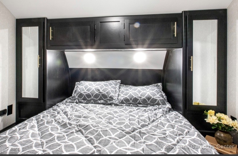 RV rental: Cozy bedroom with gray patterned bed, dark overhead and mirrored side cabinets, and bright reading lights.. Forest River Cherokee 2021