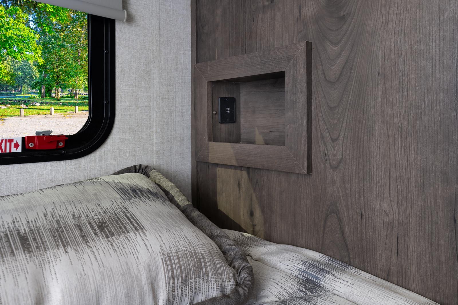 Cozy RV rental interior with a bed, scenic window view, and a convenient bedside nook with a charging port.. Gulf Stream Conquest 2022