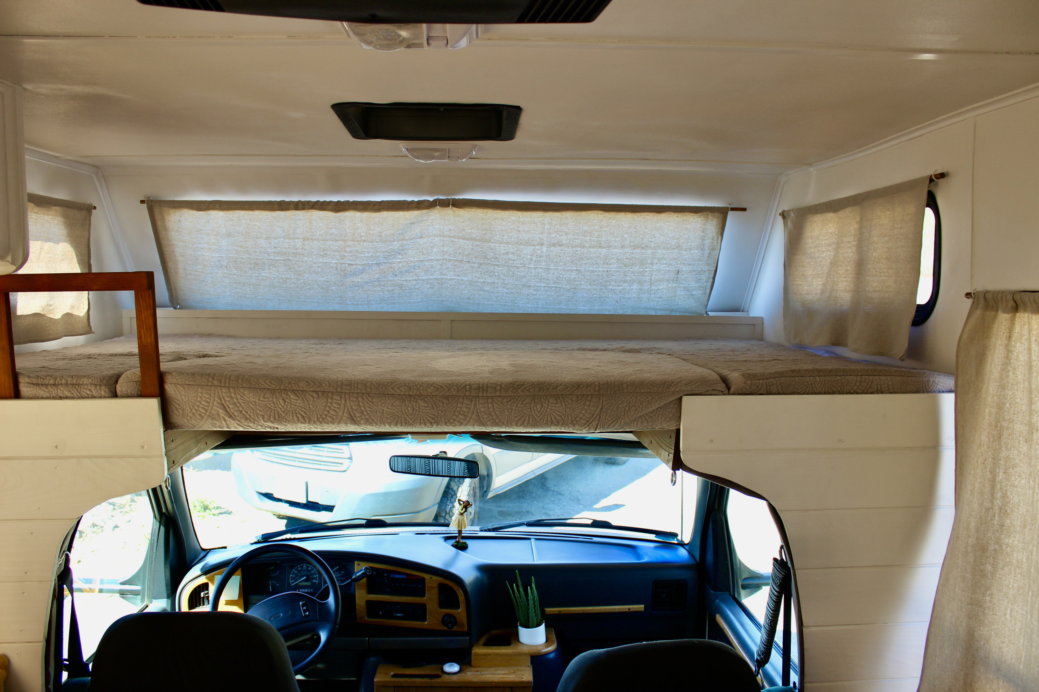 Cozy RV rental interior with an over-cab bed, showing the neatly arranged sleeping area and the driver's cabin below.. Gulf Stream Conquest 1995