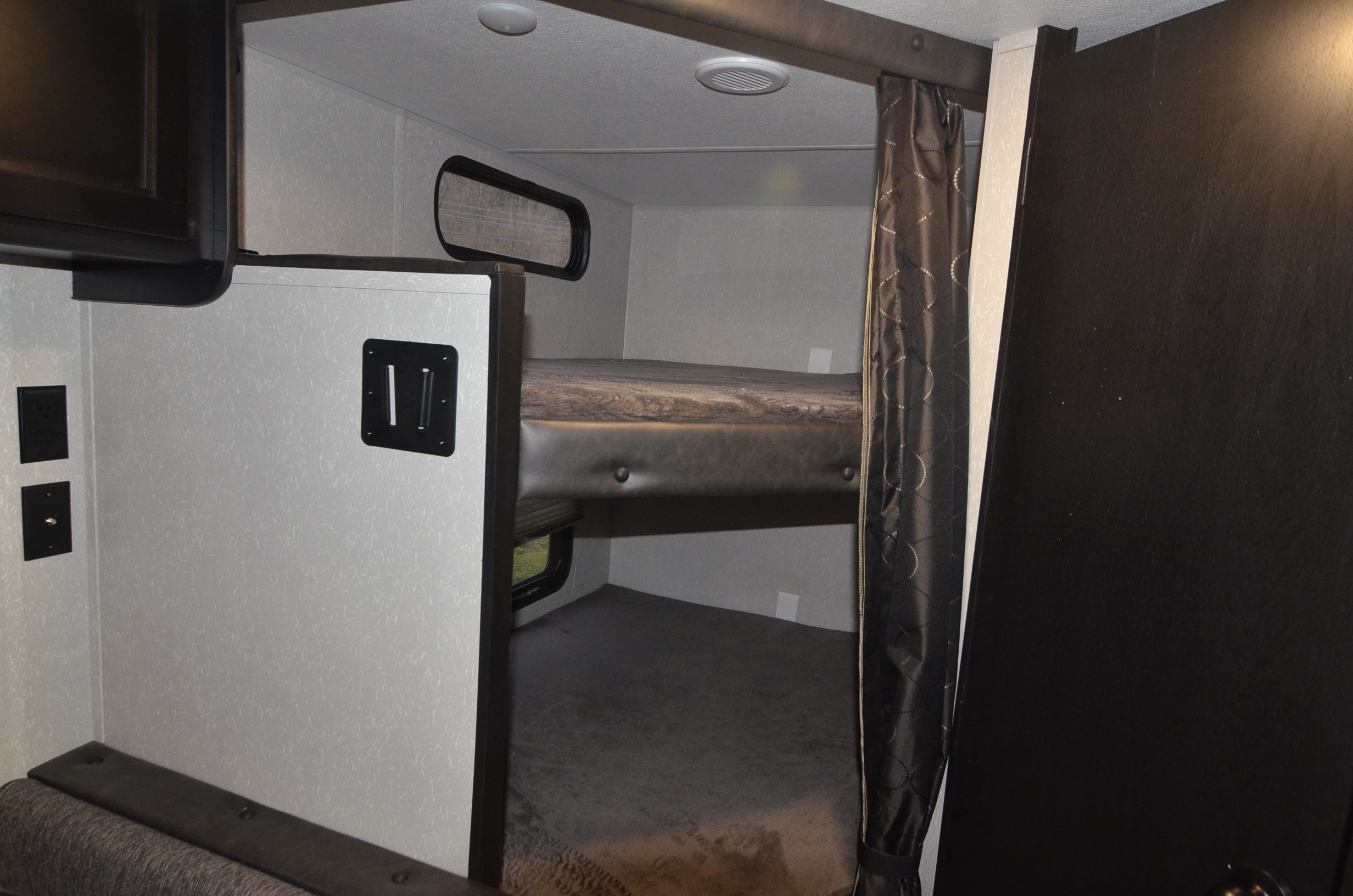 RV rental interior: Cozy bunk beds with window and TV mount, ideal for family adventures in a compact RV.. Forest River Cherokee 2021