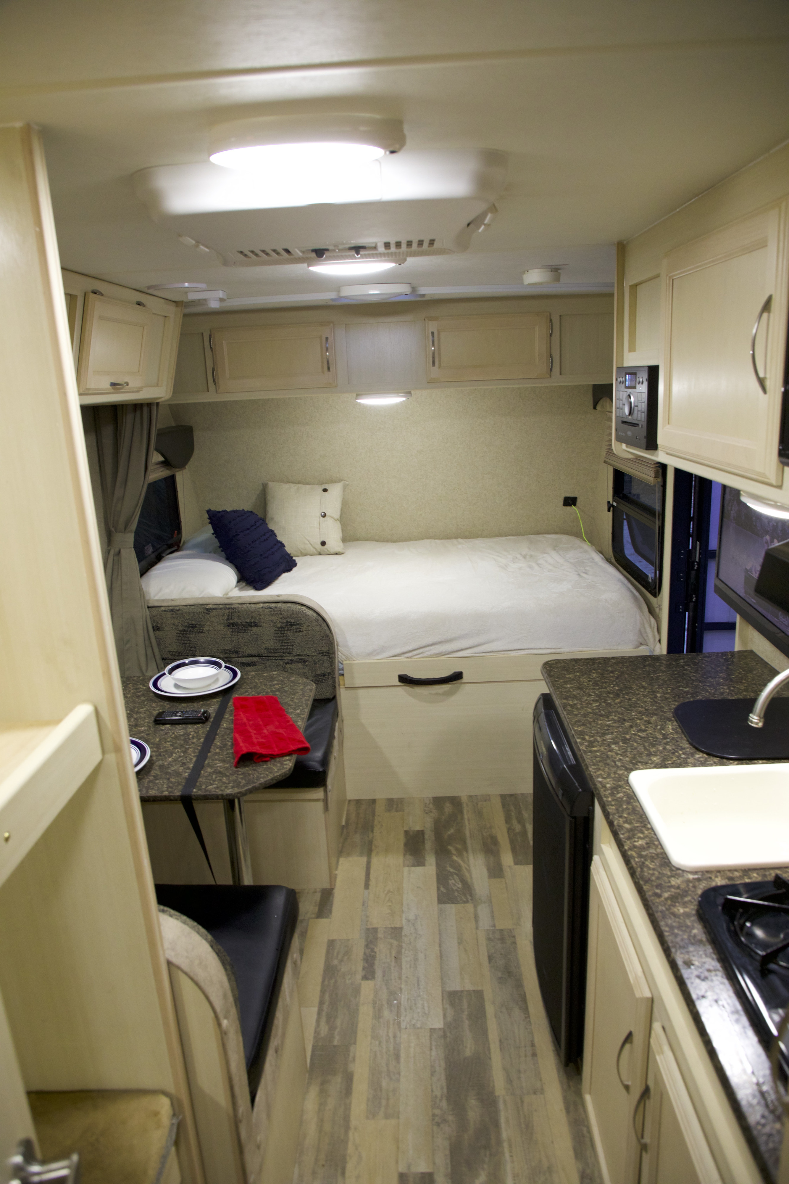 Compact RV rental interior featuring a bright bed, dining booth, and functional kitchen with light wood-look accents.. Winnebago Micro Minnie 2018