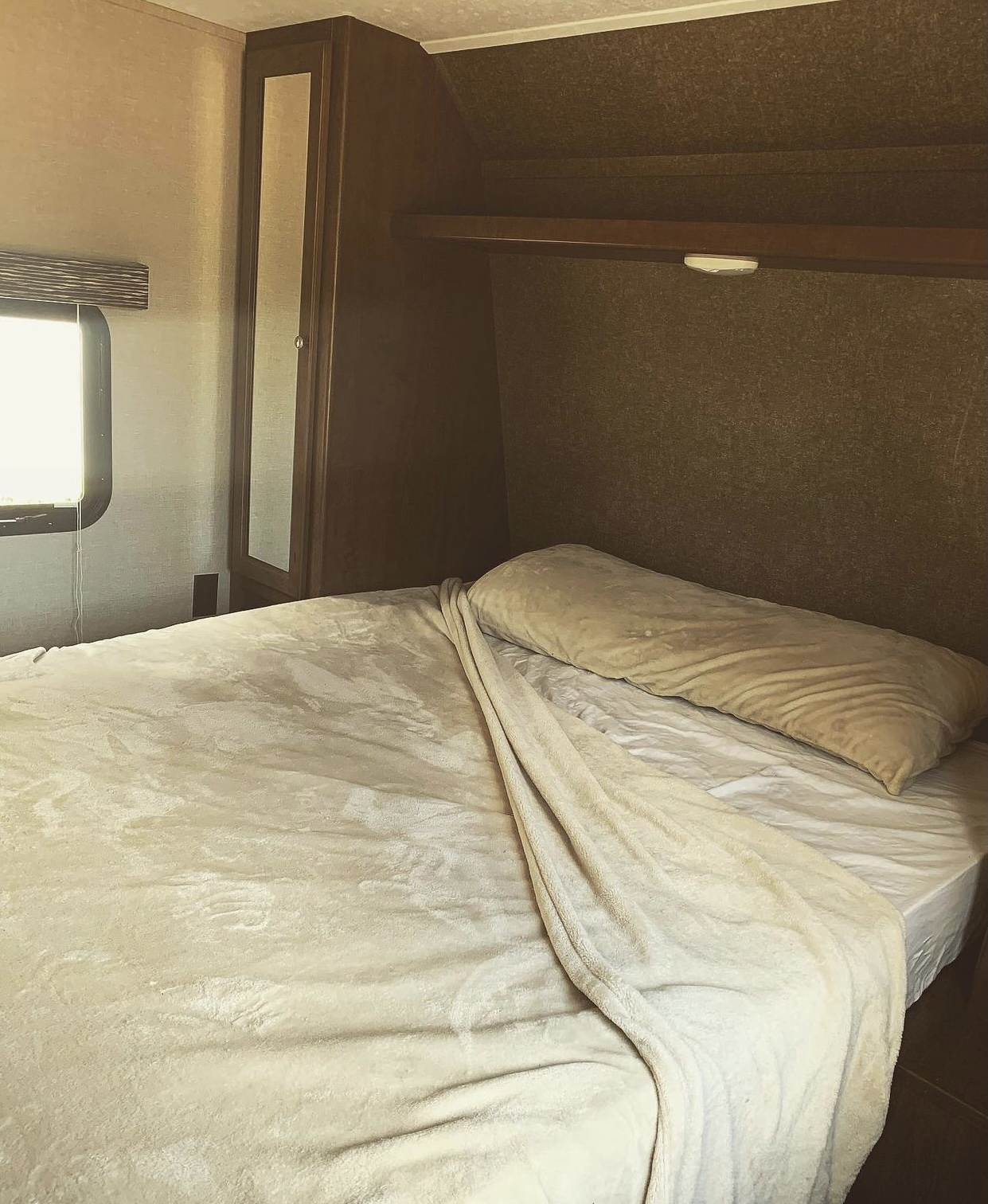 RV rental bedroom: Cozy bed, window, shelf, and mirrored closet in a travel trailer.. Keystone Hideout 2018