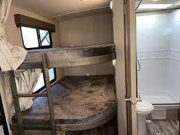 RV rental interior: two bunk beds with patterned mattresses and windows, plus a compact bathroom with a shower.. Grand Design Imagine 2800BH 2019