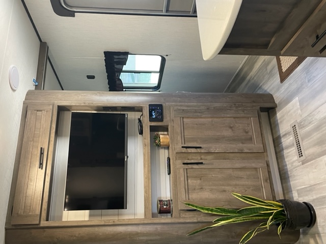 This RV rental features a modern wood entertainment center with a TV, ample storage, and decor, creating a cozy living space.. Heartland Pioneer 2021