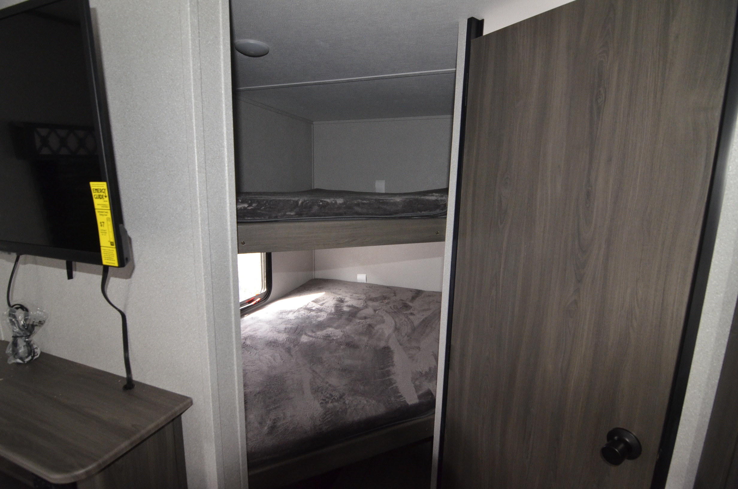 RV rental interior: cozy bunk beds with bedding, a wall-mounted TV, and a closed door. A compact space for travel.. Forest River shasta 2021