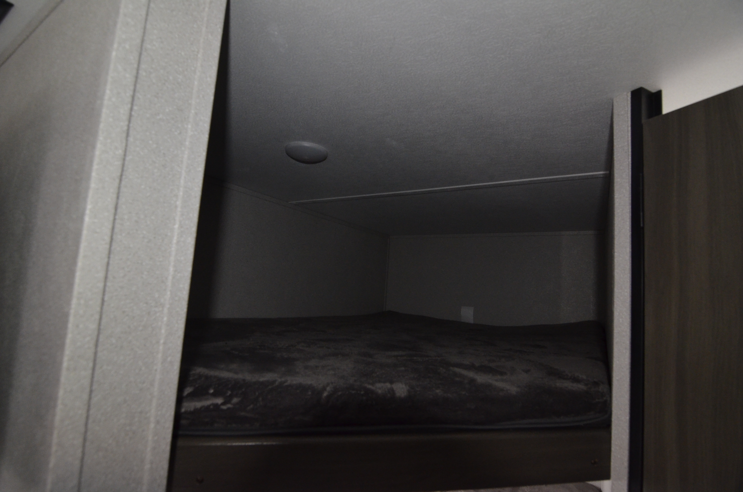 Cozy bunk bed interior of an RV rental, featuring a dark mattress and overhead light, ideal for compact travel.. Forest River shasta 2021