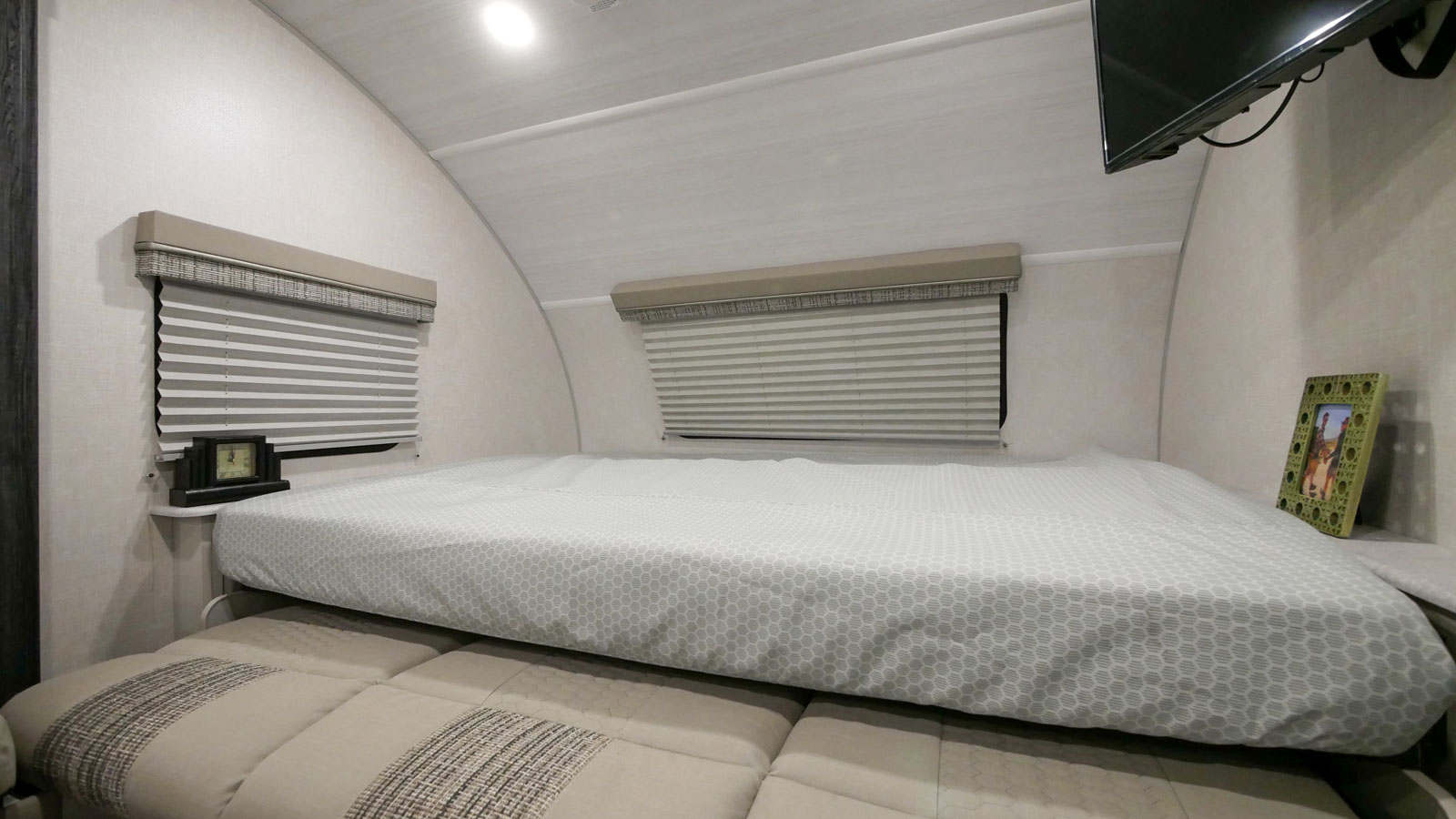 Comfortable RV rental bedroom featuring a cozy bed with patterned sheet, window blinds, and compact storage. Ready for travel.. Forest River R-Pod 2022