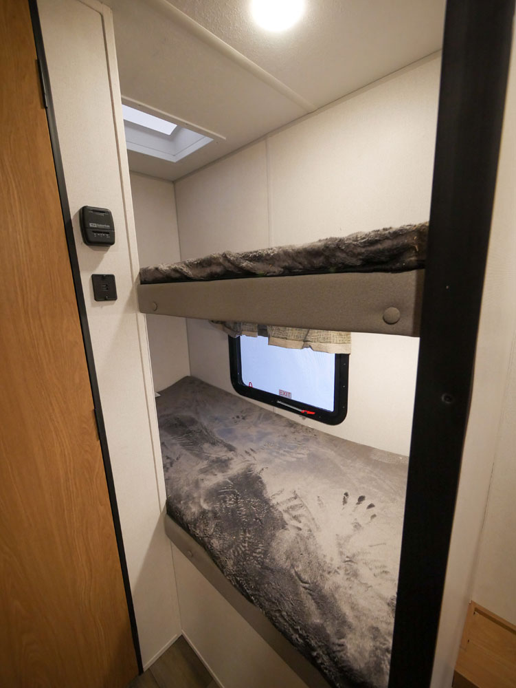 Inside this RV rental: functional bunk beds. The lower bunk's textured mattress displays clear hand and shoe prints.. Prime Time Avenger 2022