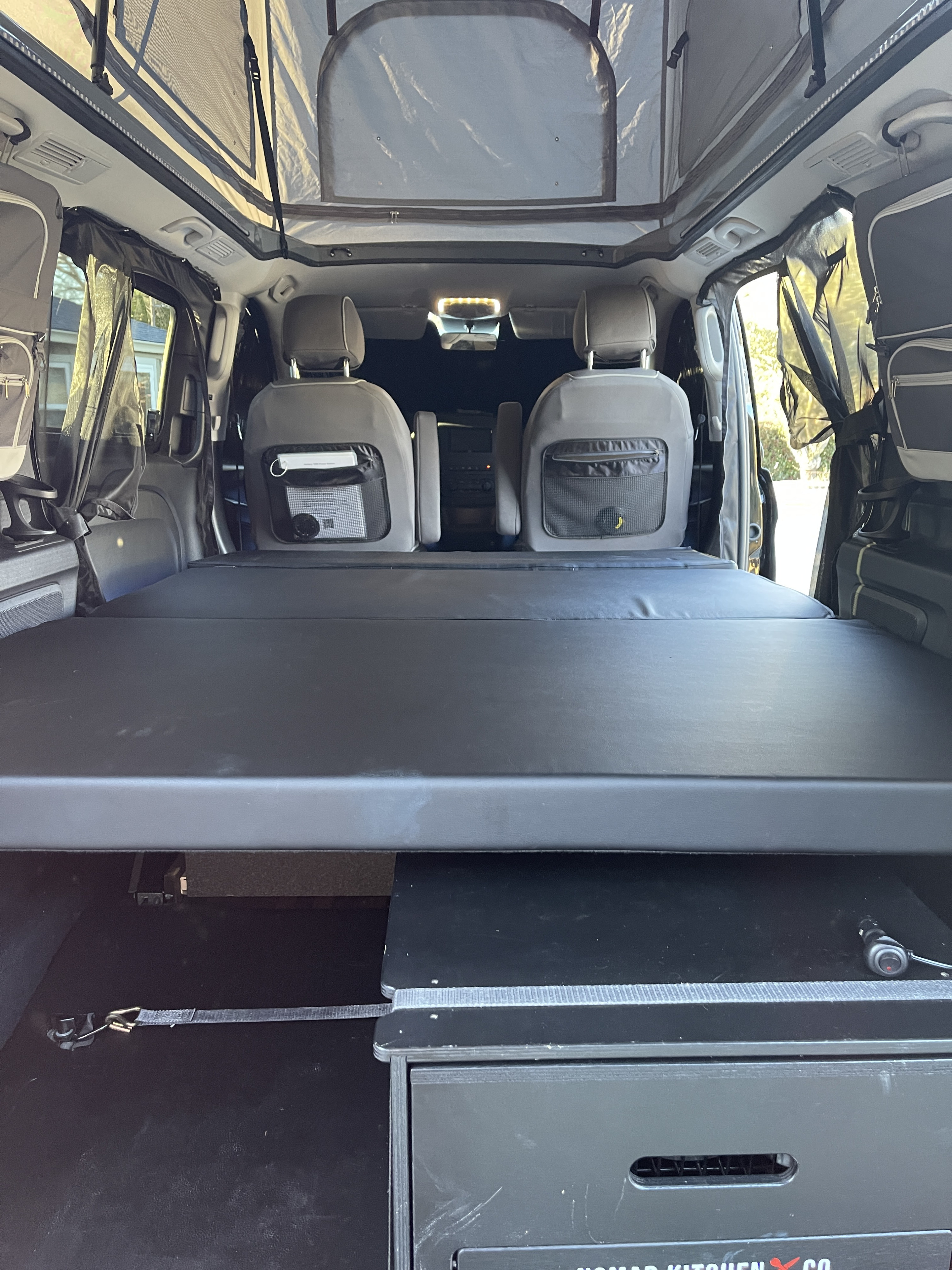 Cozy RV rental interior with a pop-top roof, bed, and integrated Nomad Kitchen system, perfect for adventure travel.. Mercedes-Benz Metris 2020