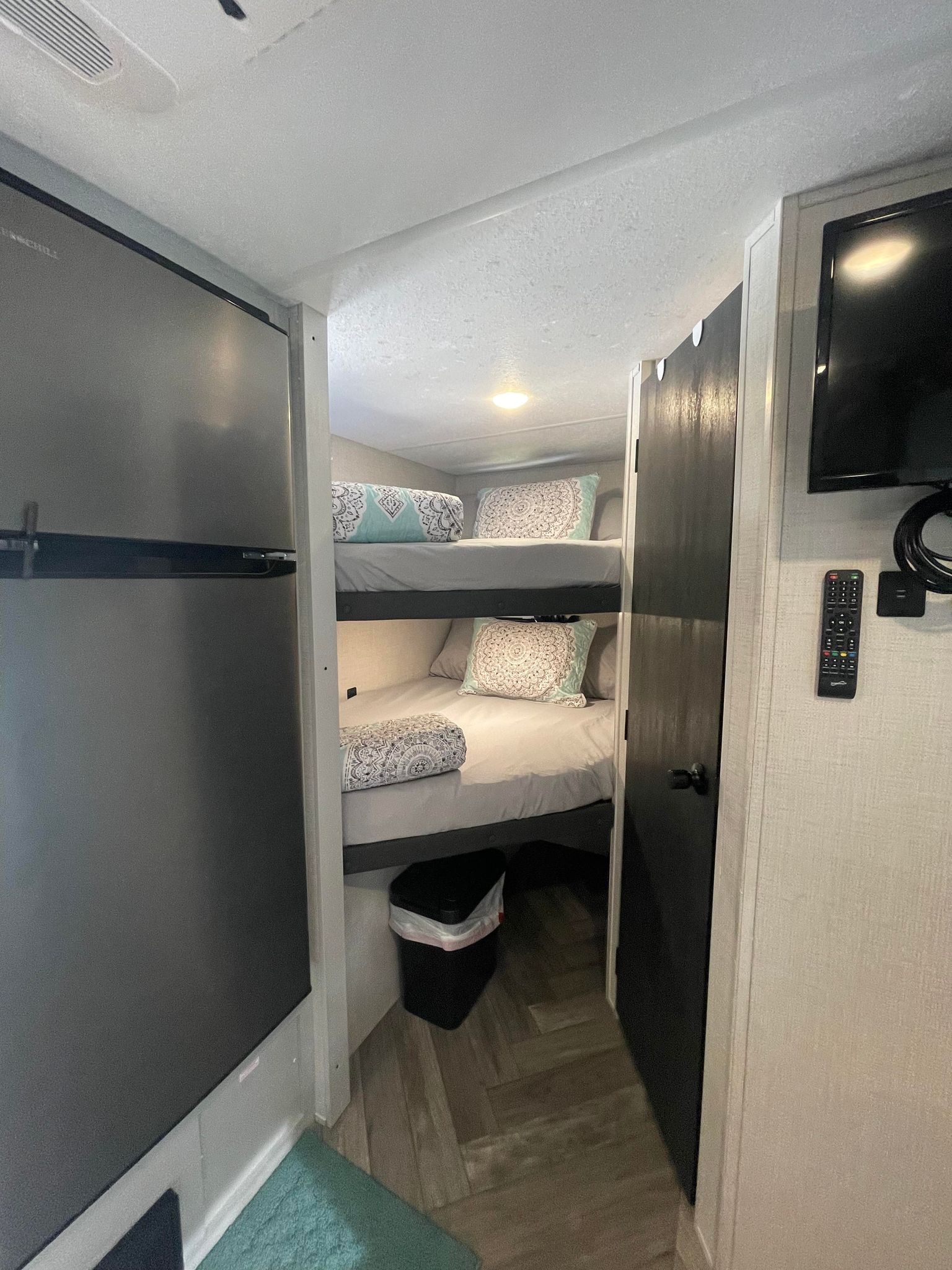 This RV rental offers a compact sleeping area with two cozy bunk beds, patterned pillows, and a refrigerator visible on the left.. Forest River Salem 2022