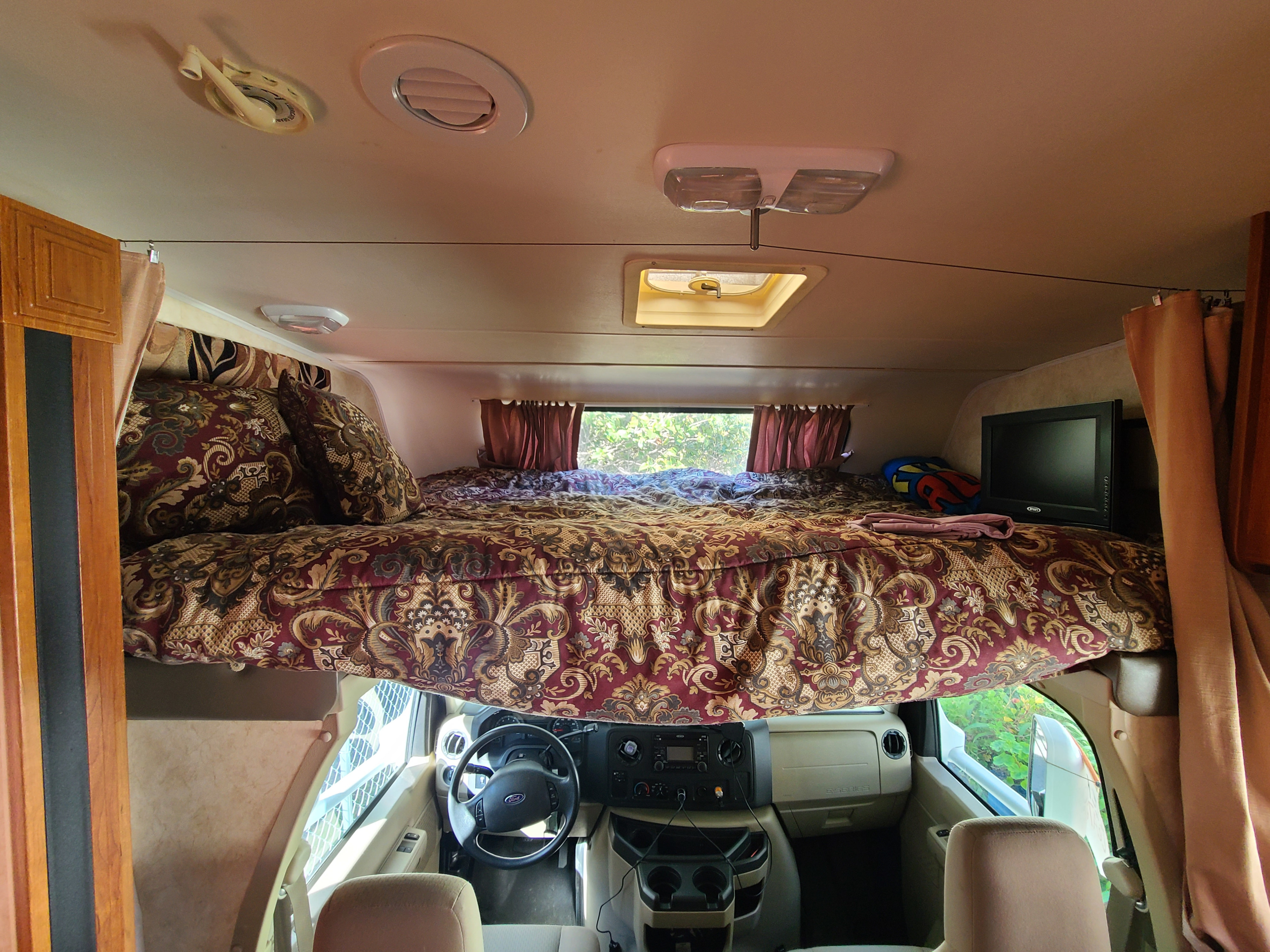 Interior view of an RV rental showing the spacious cab-over bed and front driver's cabin area. Relaxing travel.. Coachmen Freelander 2011