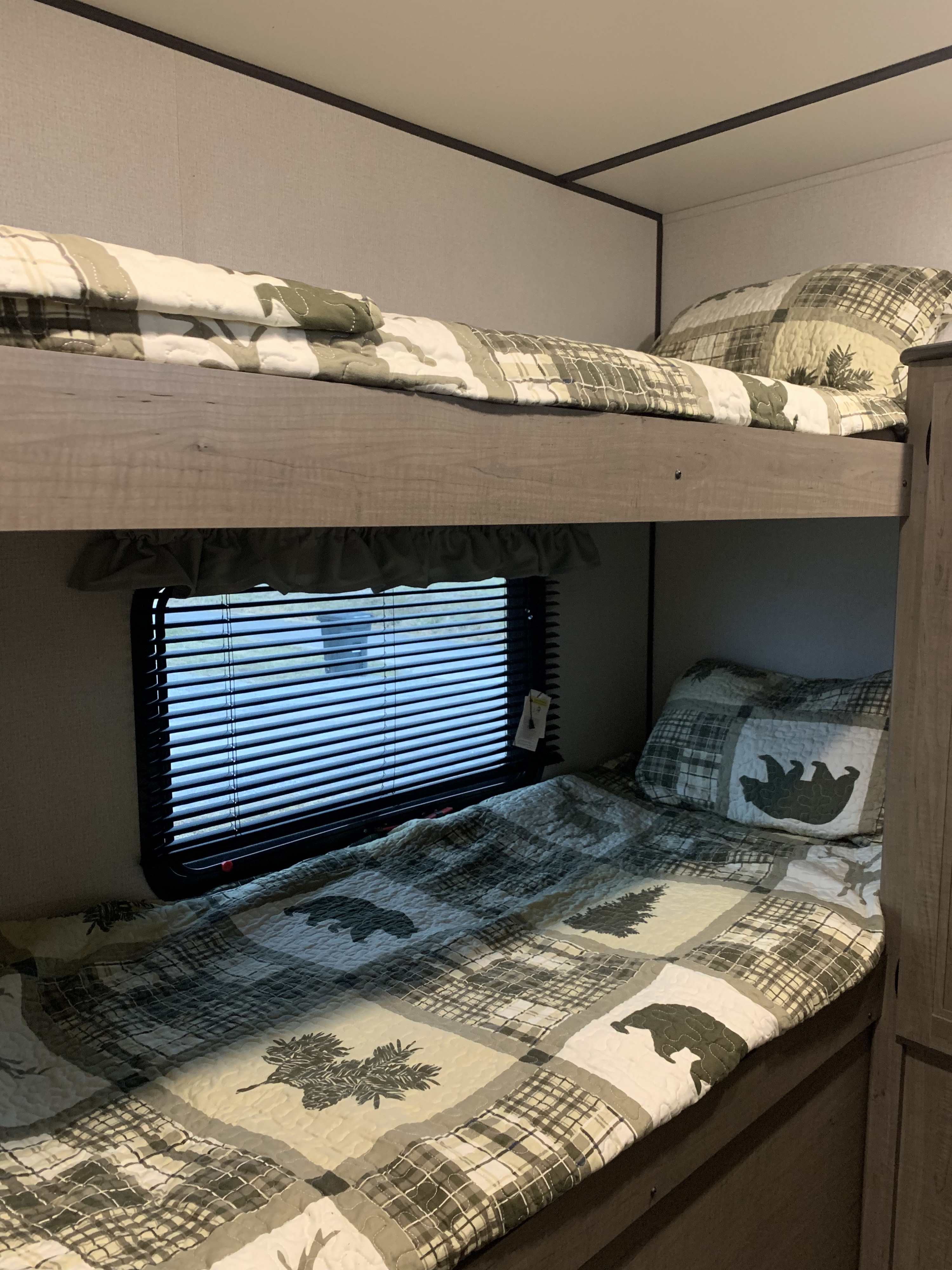 Cozy RV rental bunk beds with bear and tree themed bedding, offering a comfortable sleeping area for your adventure.. Keystone Hideout 2020